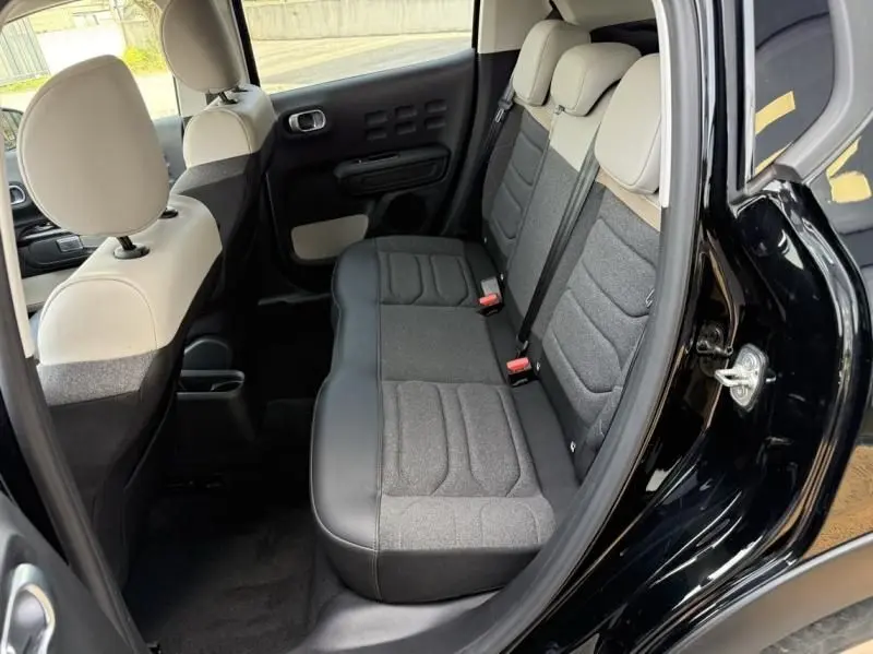 Vue intérieure arrière côté droit de la Citroën C3 2021 noire avec toit blanc, sièges bicolores gris et beige.