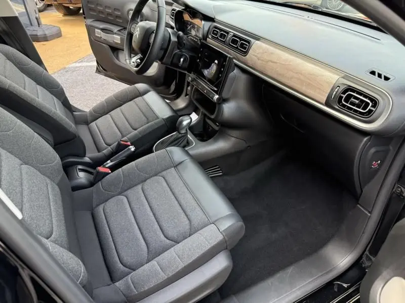 Intérieur avant droit d'une Citroën C3 2021 noir toit blanc, avec sièges gris et tableau de bord à finition bois clair.
