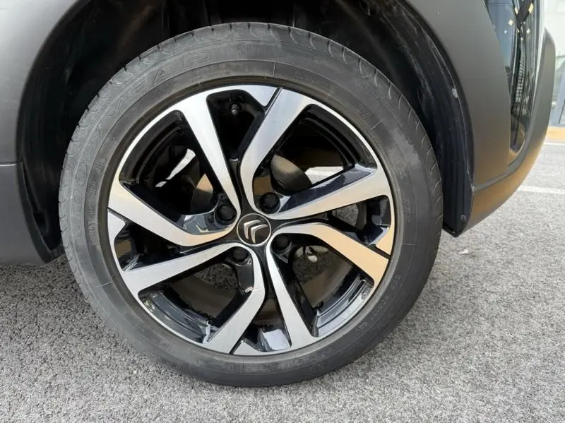 Gros plan sur la jante avant droite noire et argentée d'une Citroën C3 2021 noir avec toit blanc, version Shine Pack.