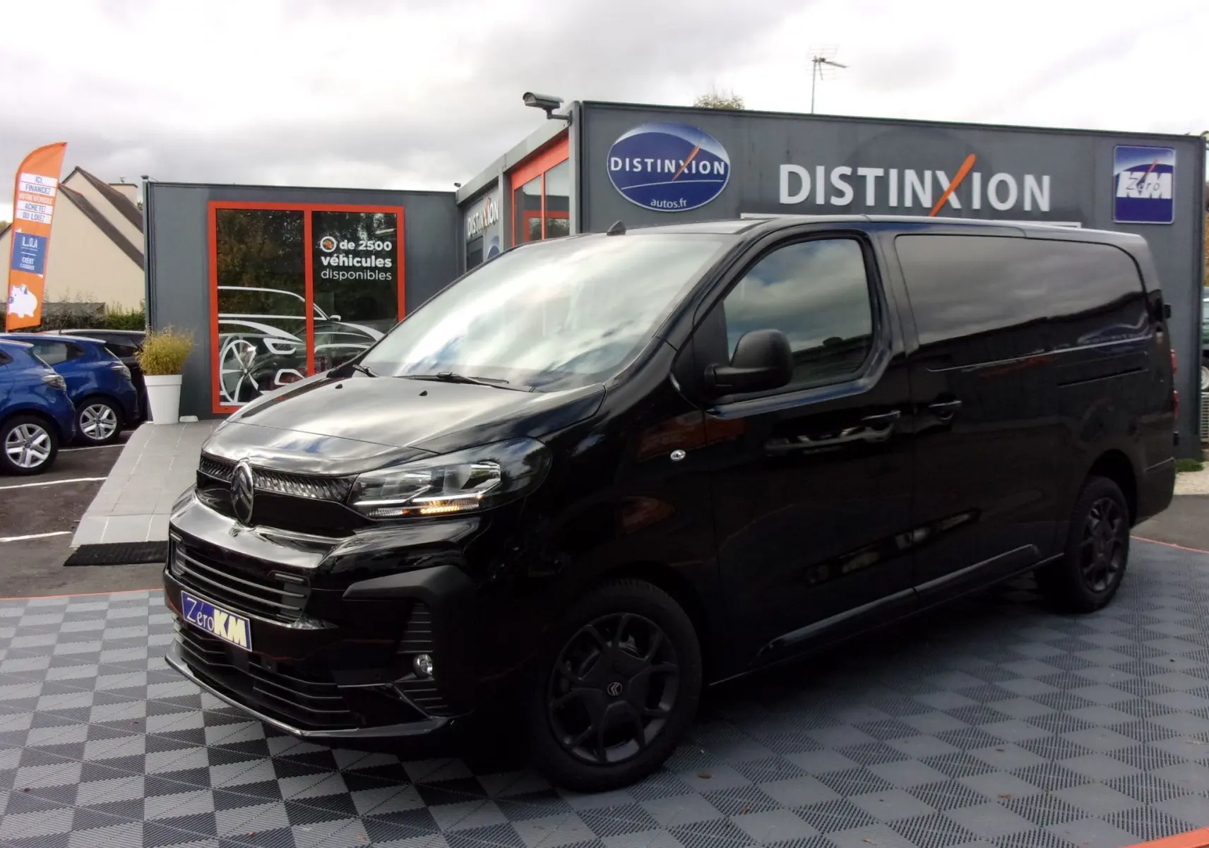 Vue 3/4 avant gauche d'un Citroën Jumpy XL noir Perla avec jantes noires, stationné devant un showroom Distinxion.