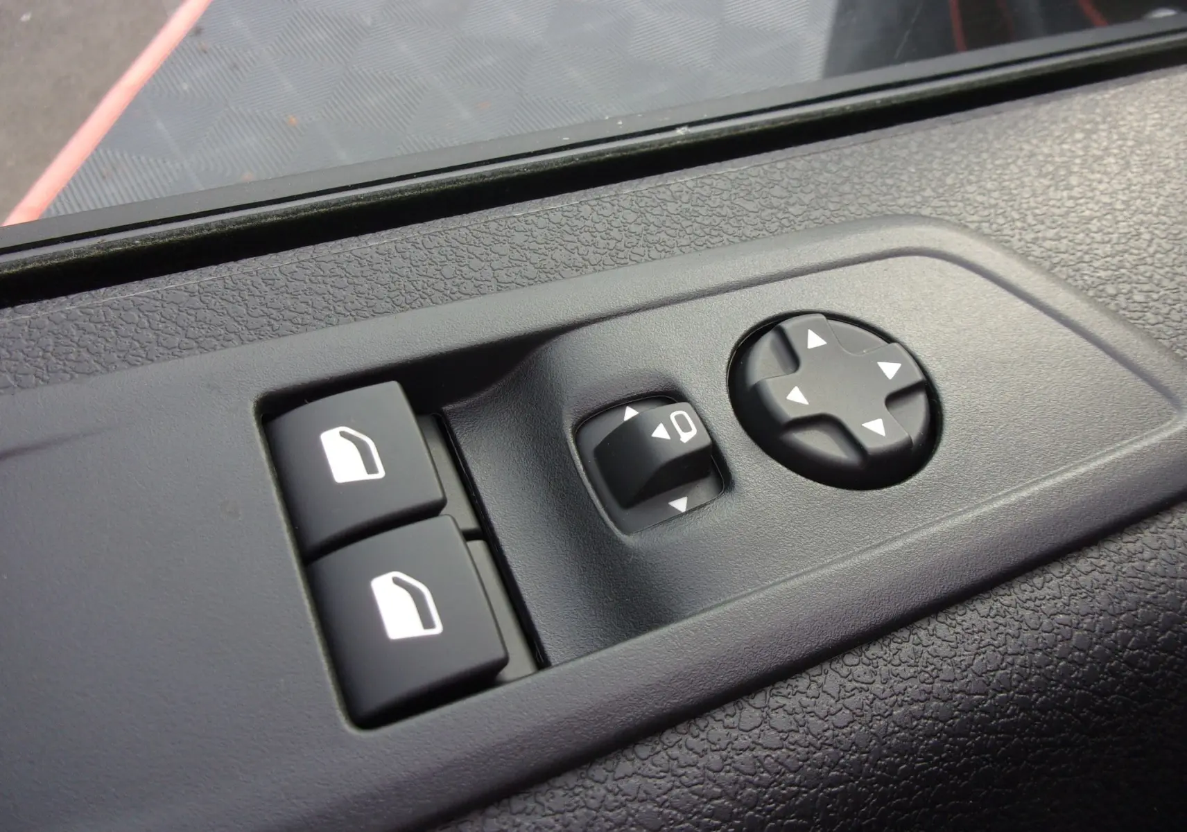 Détail des commandes de réglage des rétroviseurs et des vitres sur la porte côté conducteur du Citroën Jumpy XL noir Perla.