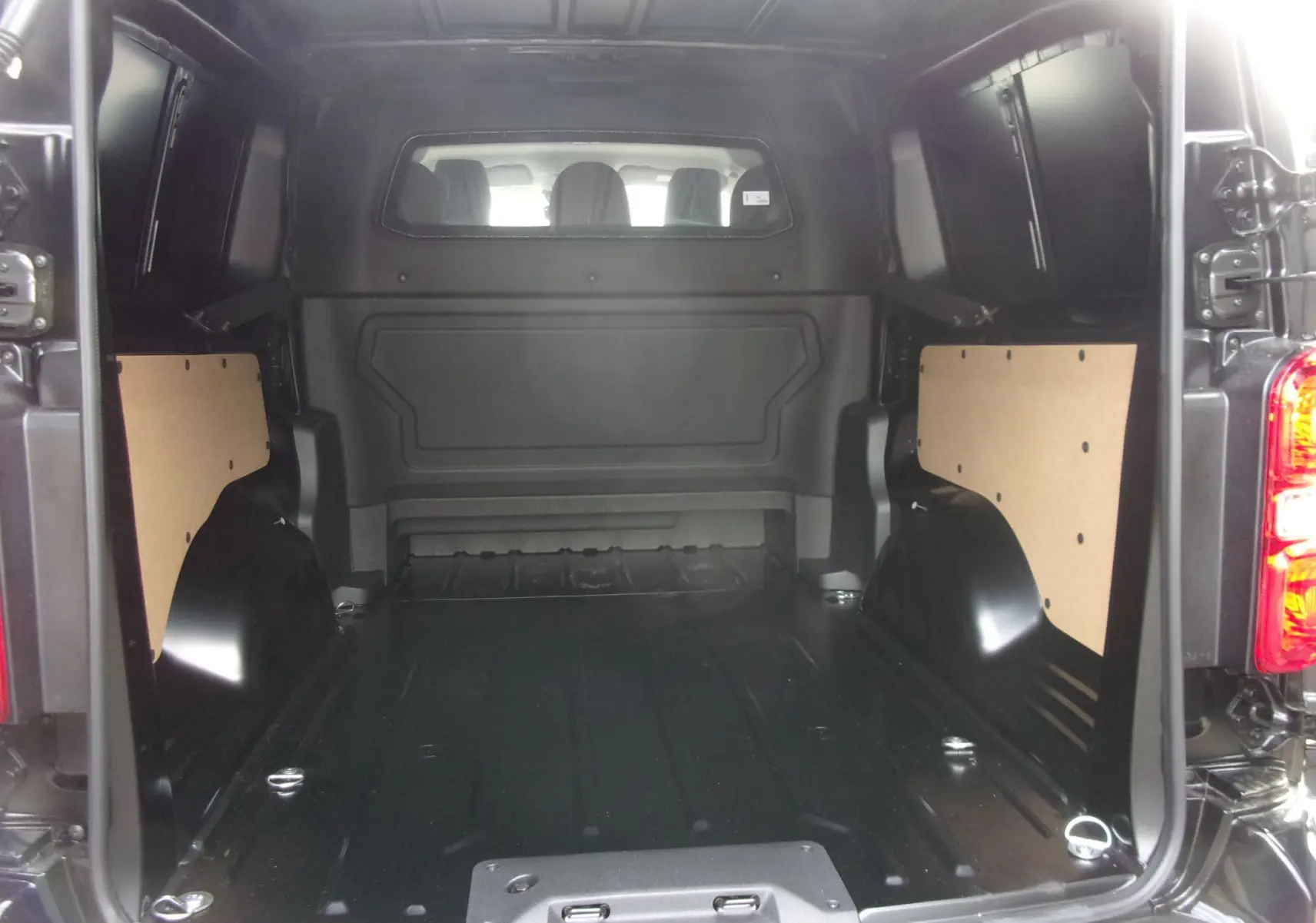 Vue intérieure arrière du Citroën Jumpy XL noir Perla, montrant la cabine approfondie et l'espace de chargement vide.