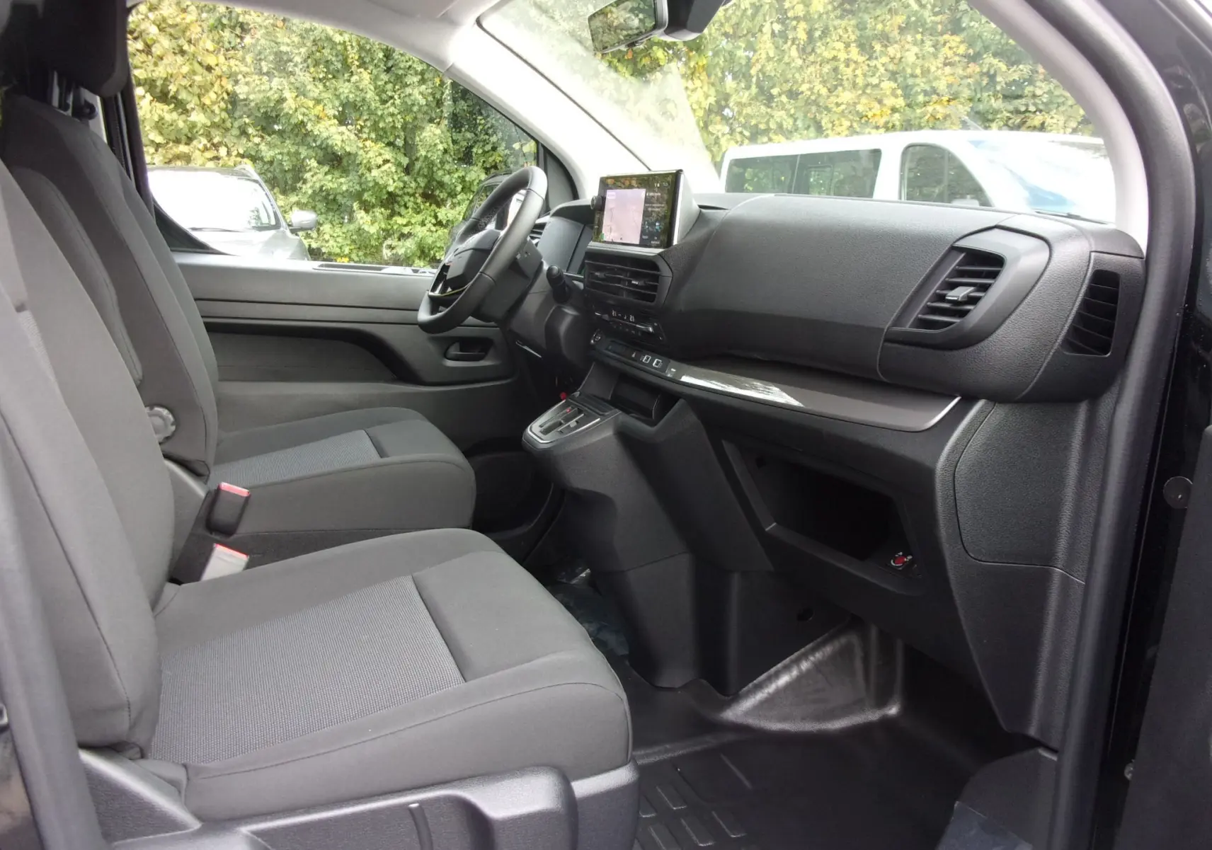 Intérieur côté conducteur du Citroën Jumpy XL noir Perla 2025, montrant sièges tissu gris et tableau de bord avec écran tactile.
