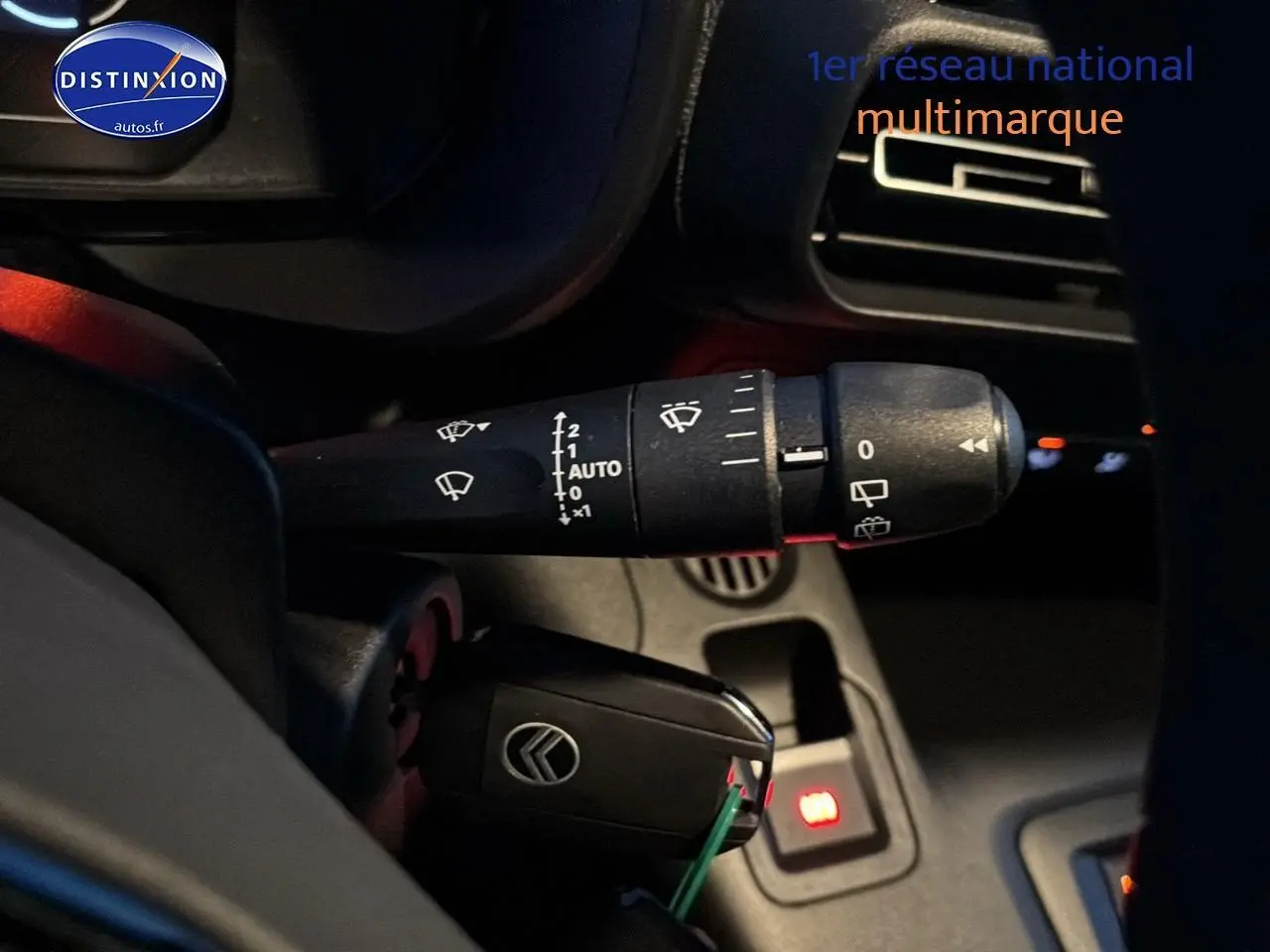 Gros plan sur la commande d’essuie-glace et la clé de contact du Citroën Berlingo Fourgon blanc, intérieur côté gauche.