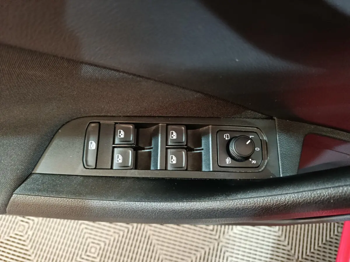 Vue rapprochée des commandes de lève-vitres et réglage des rétroviseurs côté conducteur du Skoda Kamiq rouge 2024.