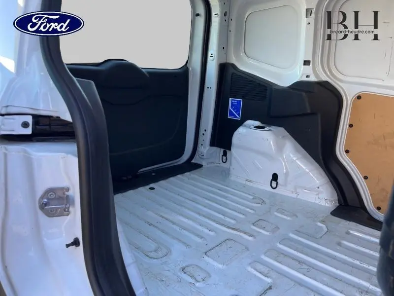 Vue intérieure du fourgon Ford Transit Courier blanc glacier, montrant l'espace de chargement côté droit avec porte latérale ouverte.