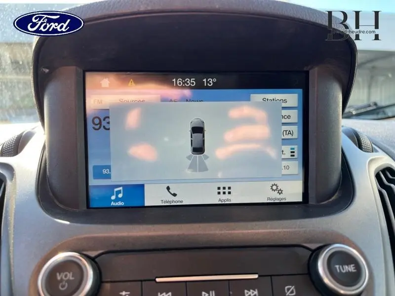 Écran tactile central du Ford Transit Courier 2019 montrant l'interface de radar de stationnement, avec commandes audio visibles.