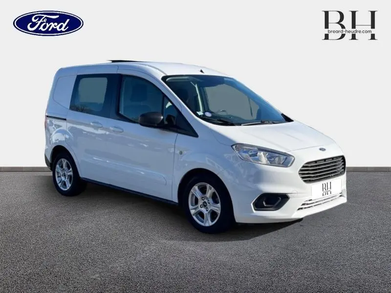 Ford Transit Courier Fourgon blanc glacier vu en 3/4 avant droit avec portes latérales vitrées et jantes alliage.