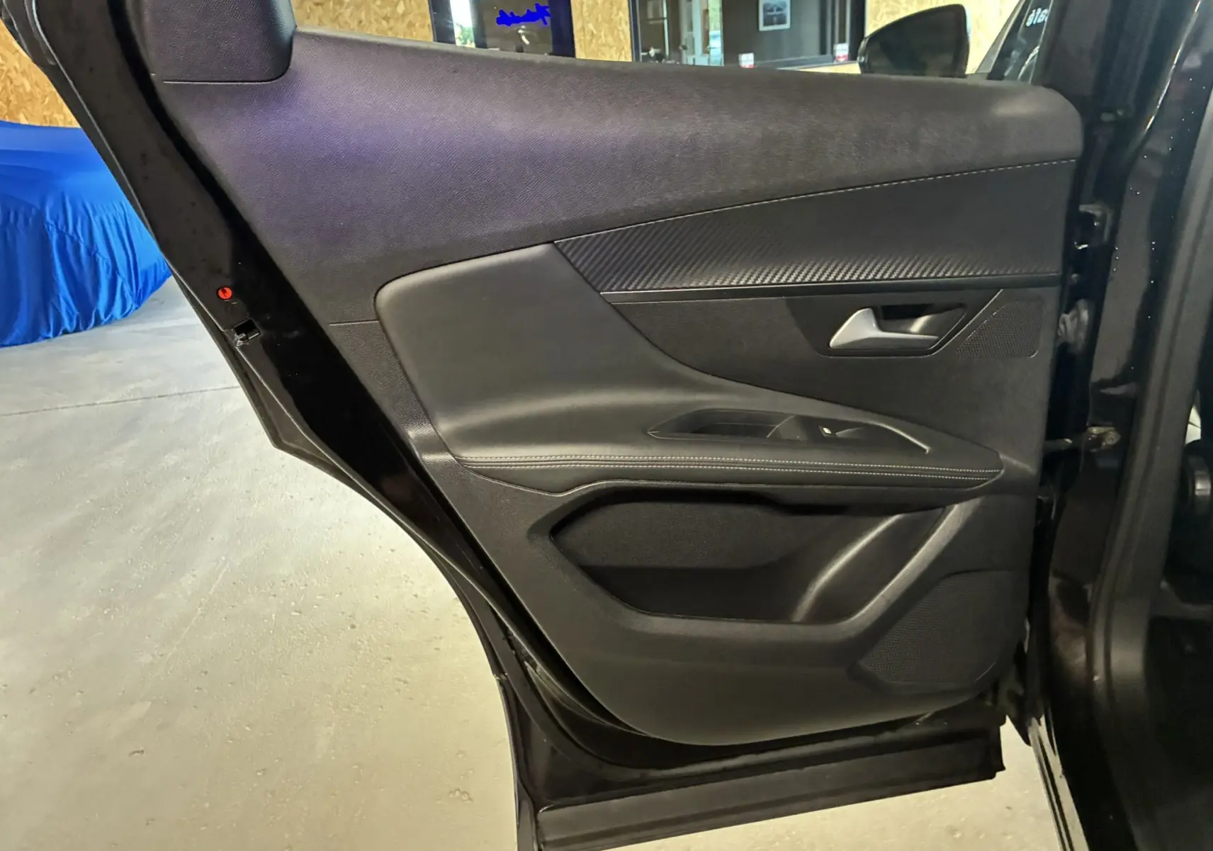 Vue rapprochée de la porte arrière droite noire d’un Peugeot 3008 1.5 BlueHDi 130 Allure Pack, intérieur tissu noir.