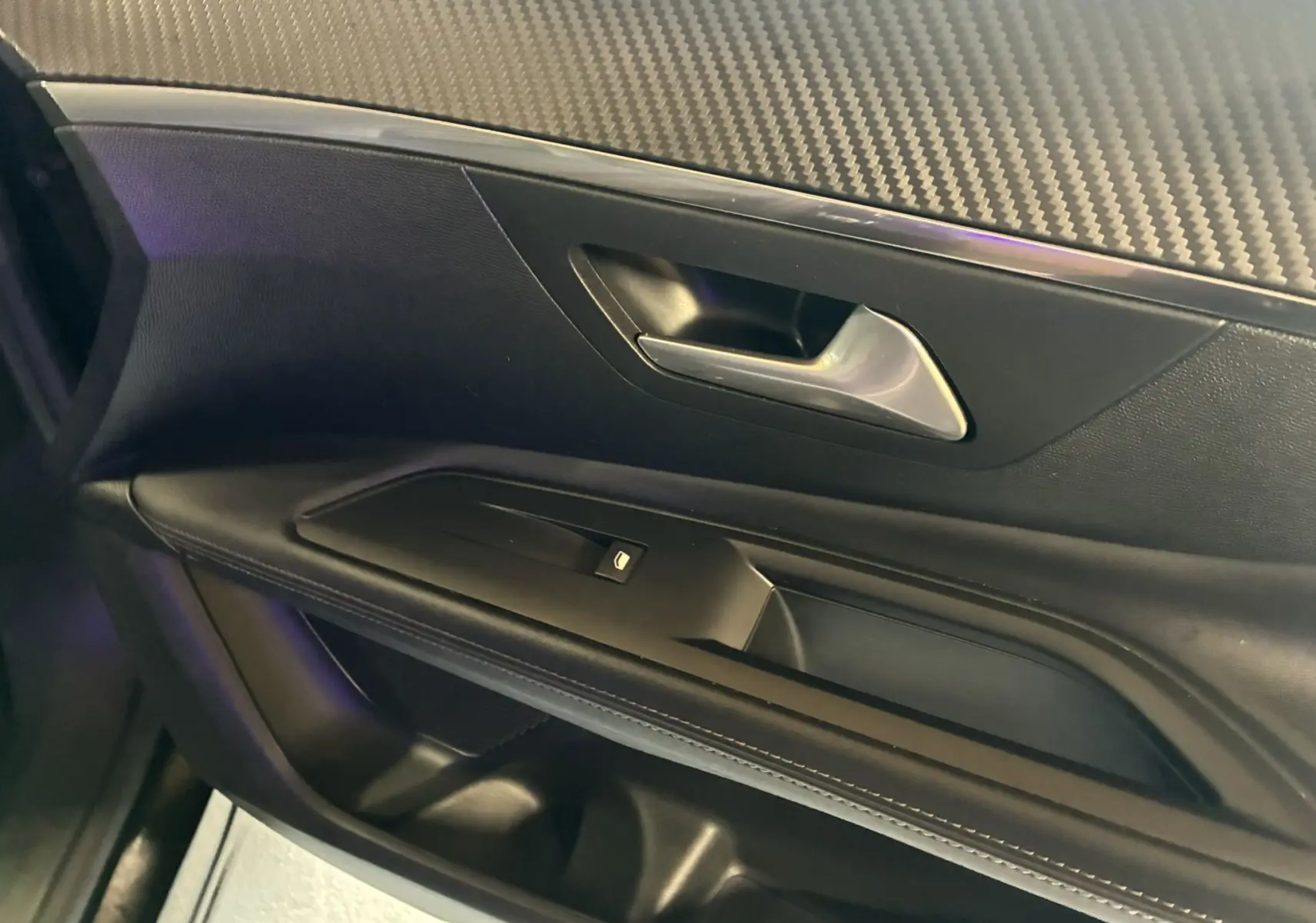 Gros plan sur la porte intérieure côté gauche du Peugeot 3008 noir, avec poignée argentée et bouton de commande de vitre.