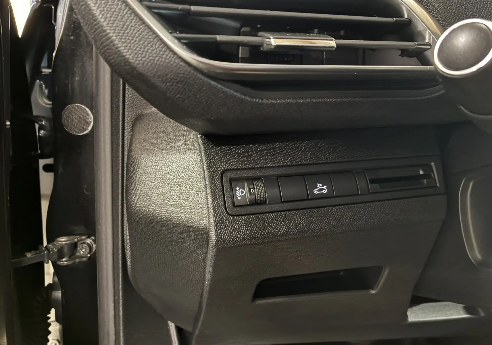 Détail intérieur côté gauche du tableau de bord noir du Peugeot 3008 1.5 BlueHDi 130 Allure Pack avec commandes éclairage et ouverture coffre.