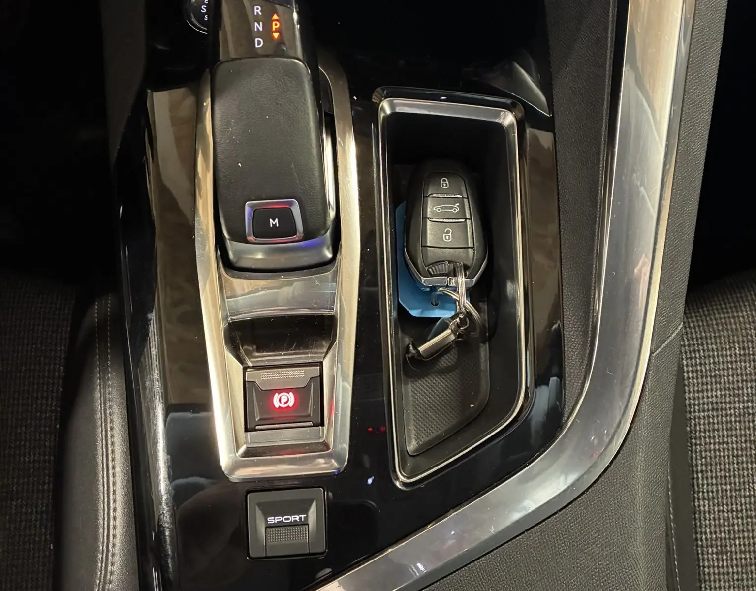 Vue en plongée sur la console centrale noire du Peugeot 3008 1.5 BlueHDi 130, avec levier de vitesse automatique et clé posée.