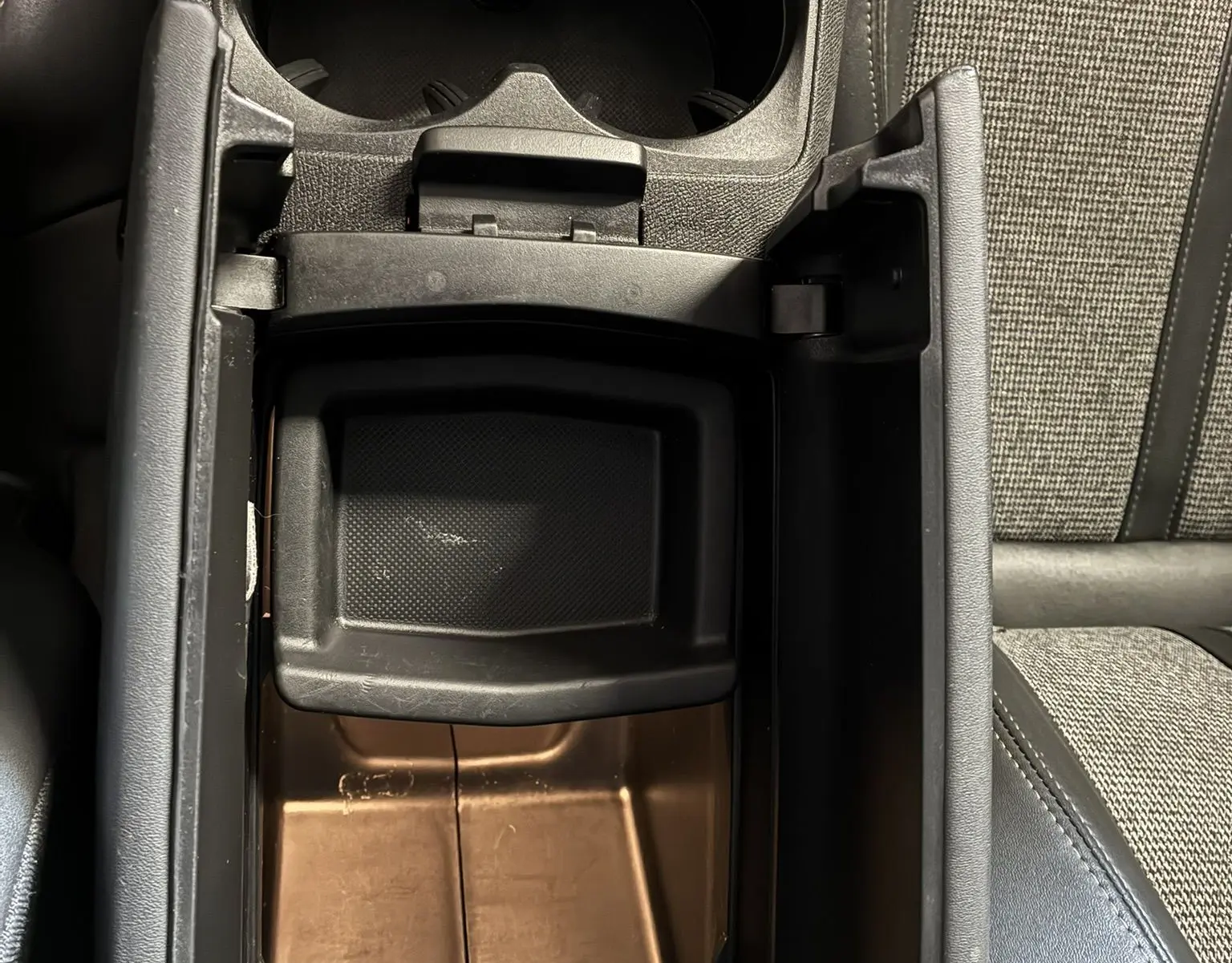 Vue plongeante sur le rangement central ouvert et porte-gobelets du Peugeot 3008 noir, intérieur tissu gris et noir.