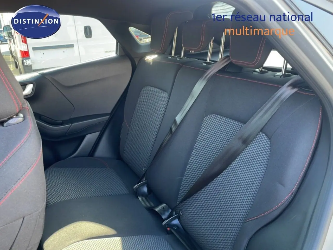 Vue intérieure arrière du Ford Puma 2023, sièges tissu noir avec surpiqûres rouges et ceintures de sécurité noires.