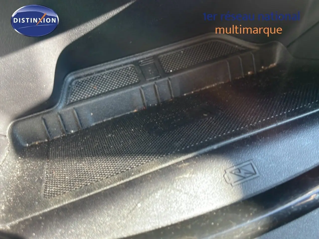 Détail du tapis de sol noir avec logo Ford dans un Ford Puma gris Solar Metal, vue intérieure basse.