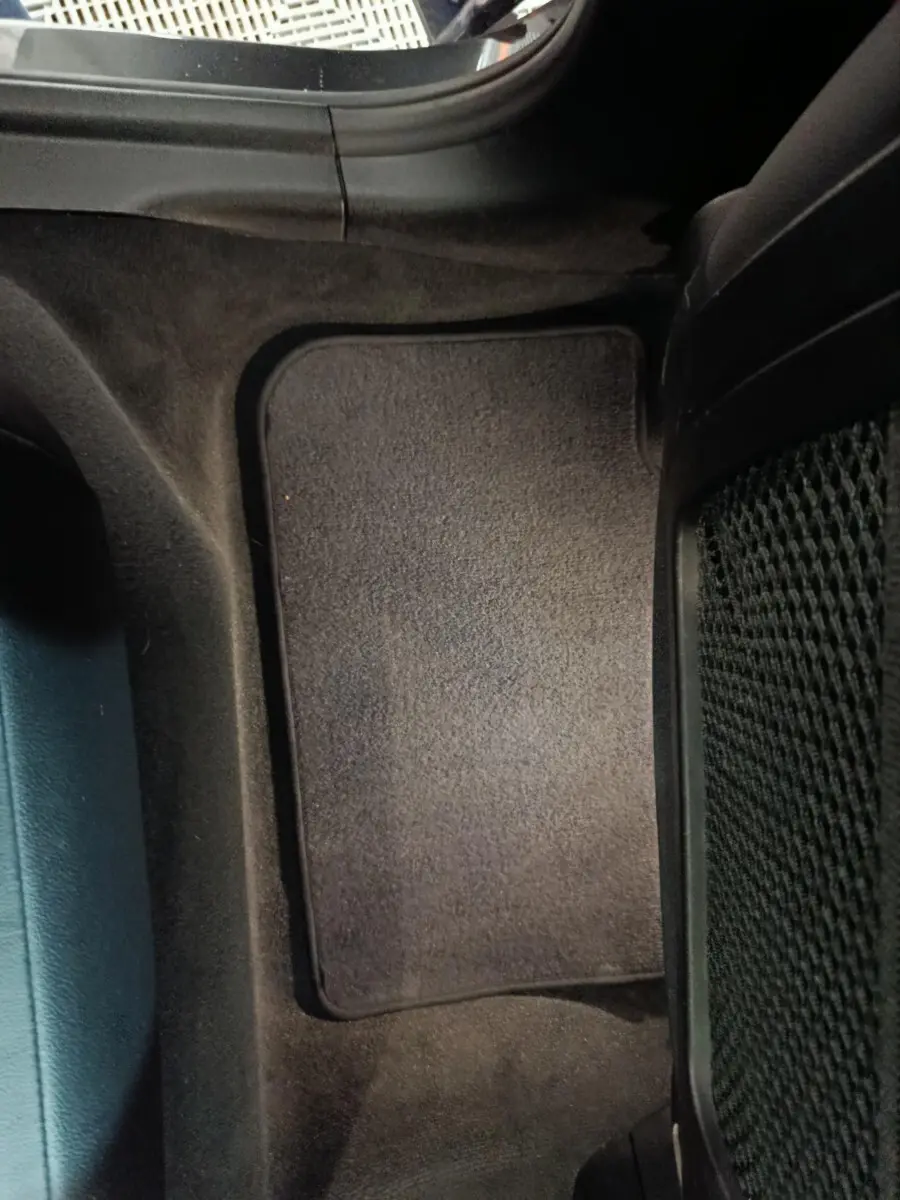 Vue rapprochée du tapis de sol noir côté arrière droit intérieur d’un BMW X3 xDrive30e gris foncé.