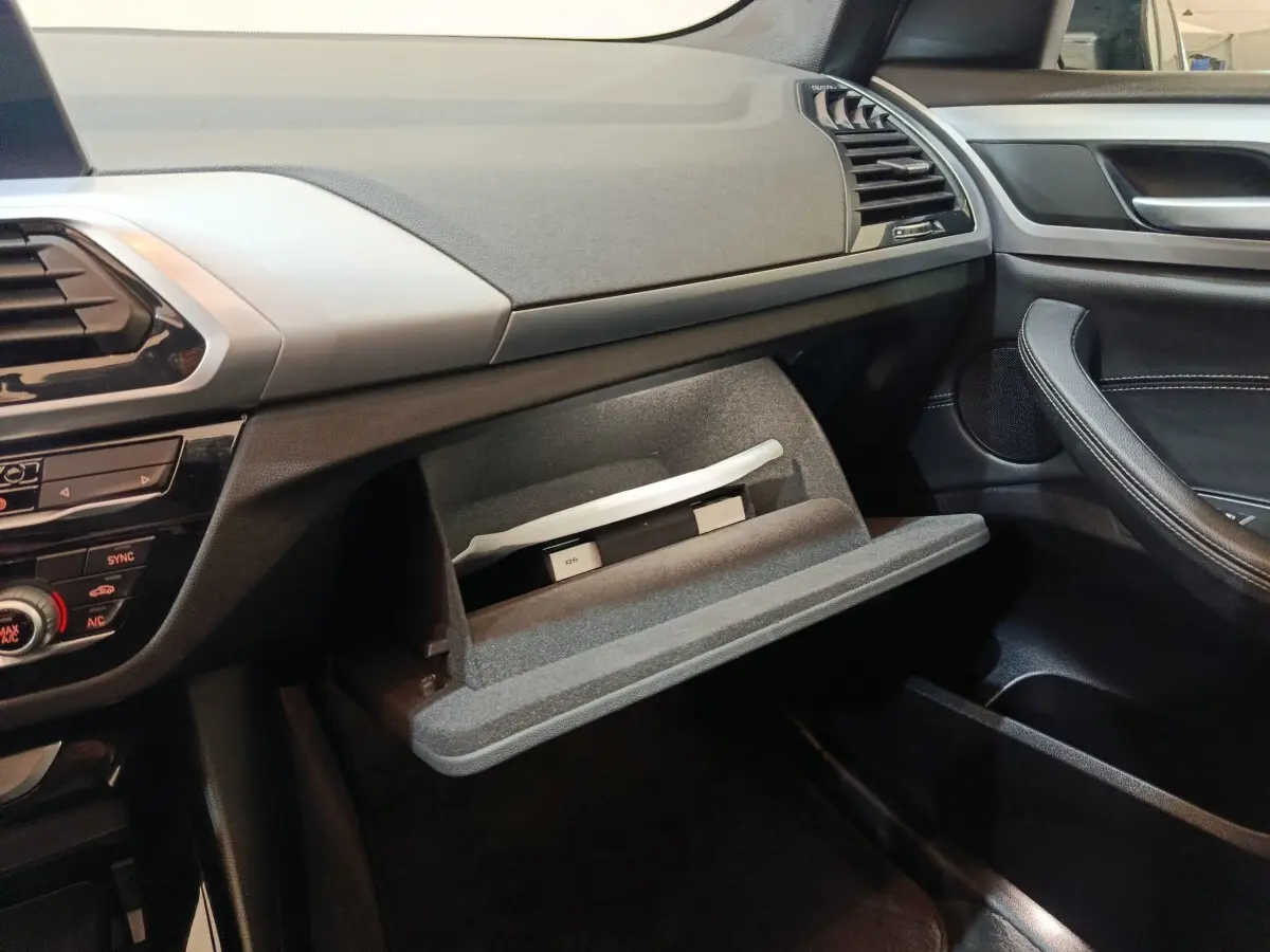 Intérieur côté passager d’un BMW X3 xDrive30e 2020 gris foncé, boîte à gants ouverte avec documents visibles.