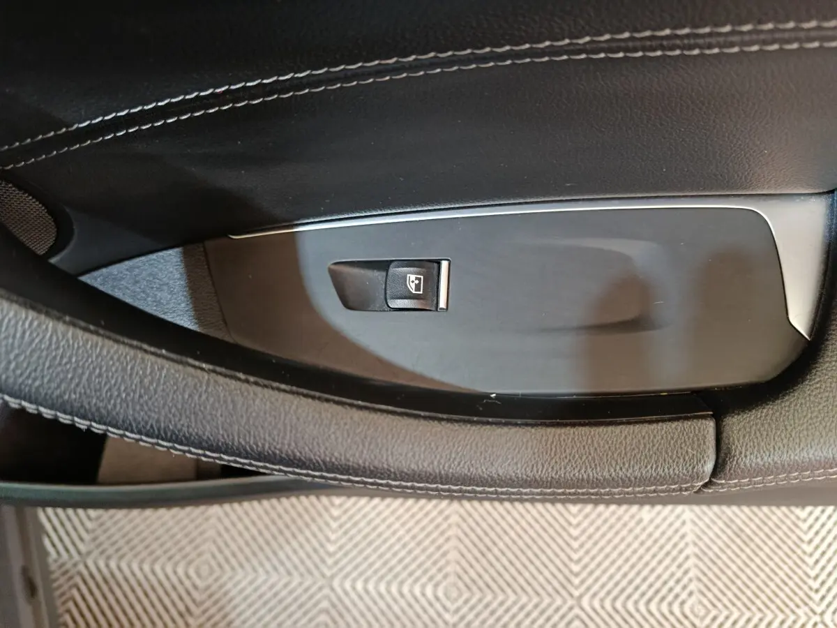 Gros plan sur le bouton de commande de lève-vitre côté gauche dans l’intérieur noir et gris foncé d’une BMW X3 xDrive30e.