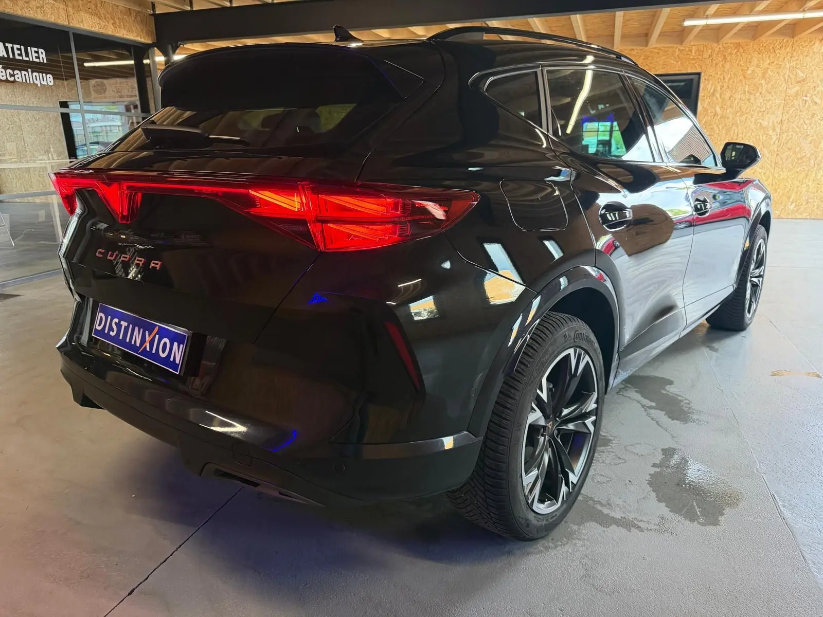 Vue 3/4 arrière droite d'un CUPRA Formentor noir avec jantes alliage 18'' TEMPEST et feux arrière LED allumés.