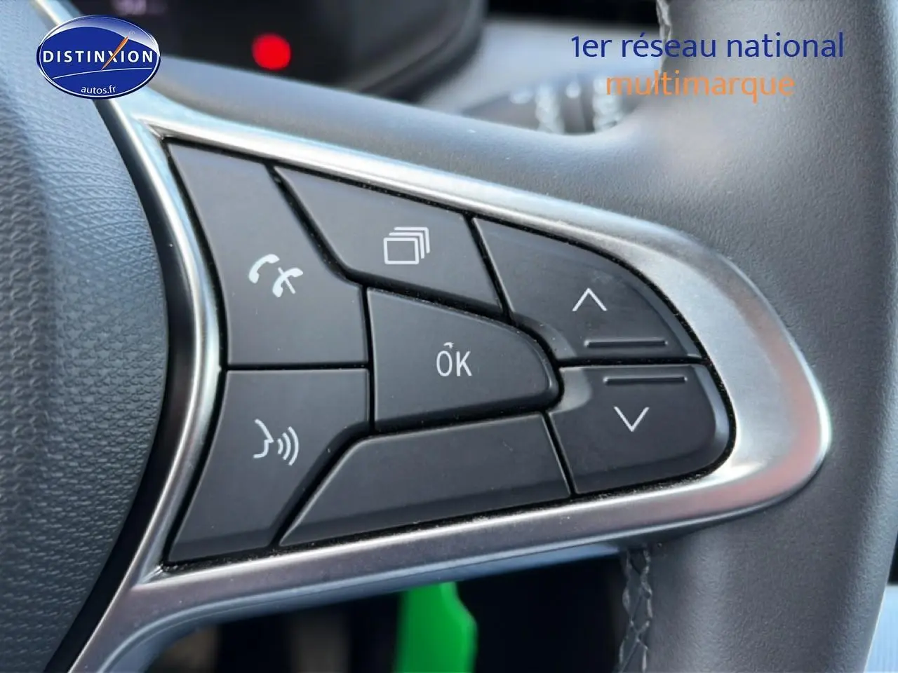 Gros plan sur les commandes multifonctions noires du volant de la Renault Clio V gris métal, finition 2025.