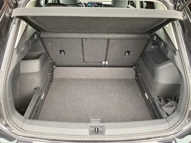 Vue arrière du coffre spacieux et noir du Volkswagen Tiguan 2024 avec banquette rabattue et habillage intérieur gris.