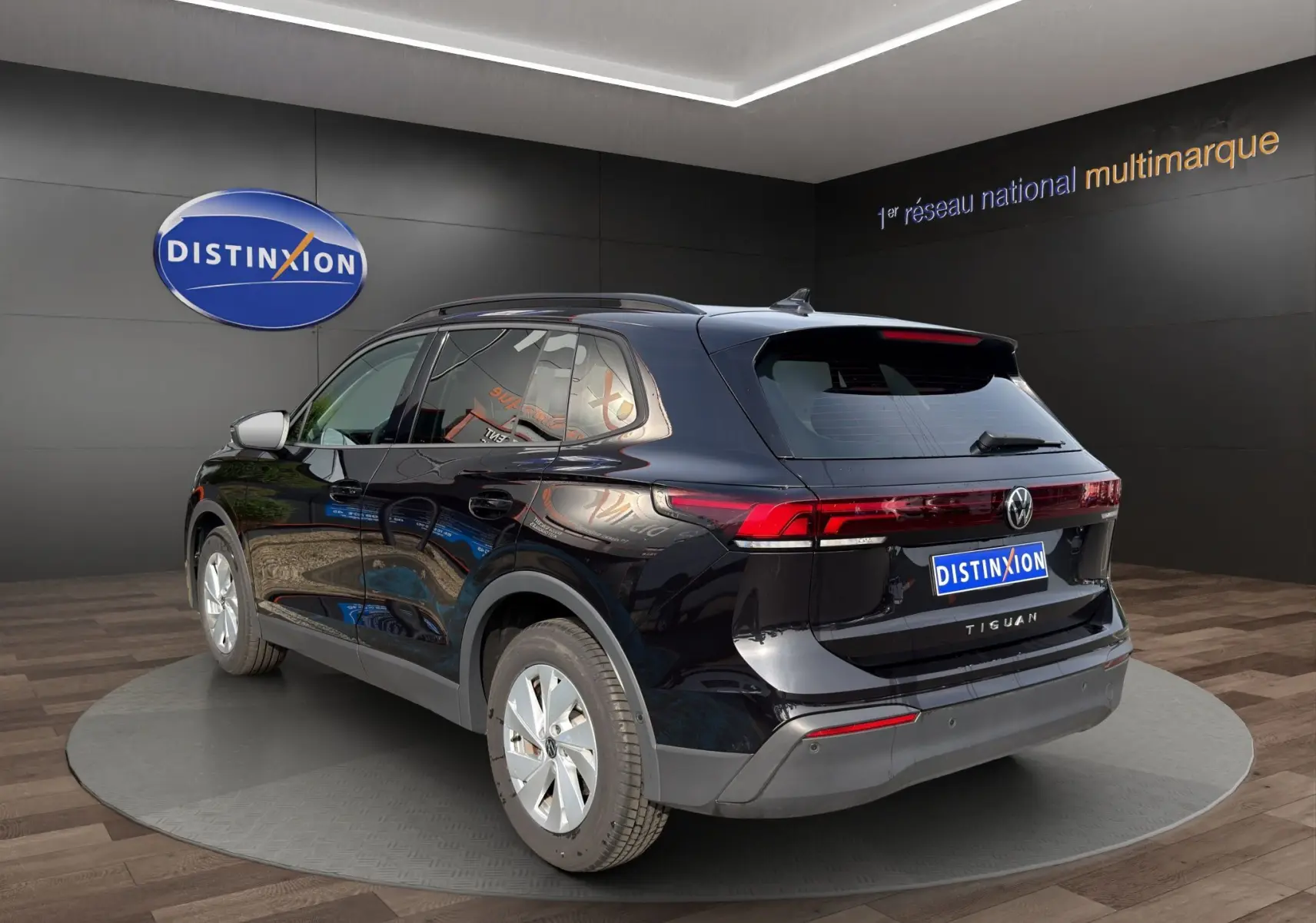 Vue 3/4 arrière droite d'un Volkswagen Tiguan noir 2024 avec feux arrière LED et vitres surteintées.