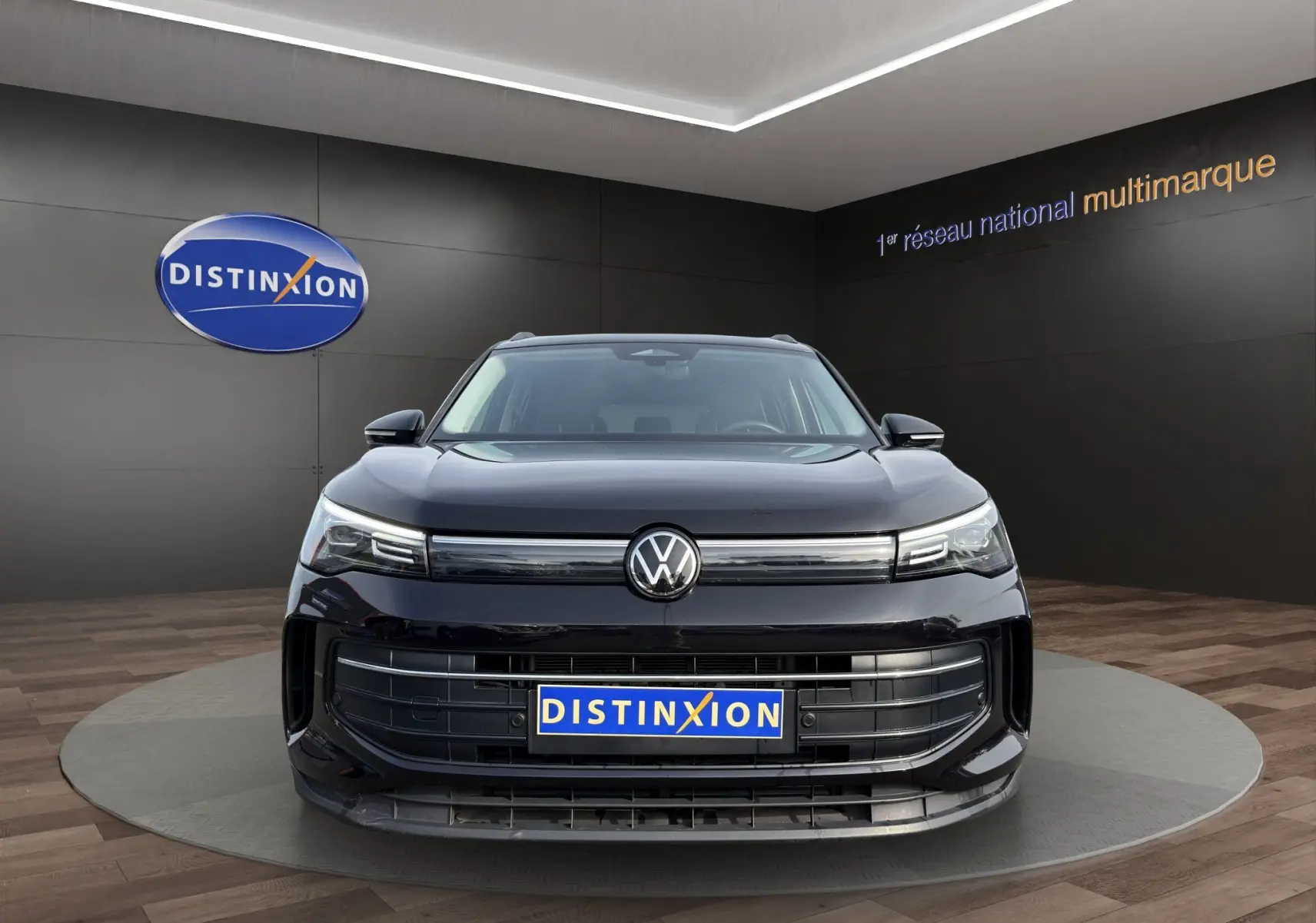 Vue avant d’un Volkswagen Tiguan noir 2024 avec calandre large et logo VW centré, en showroom Distinxion.