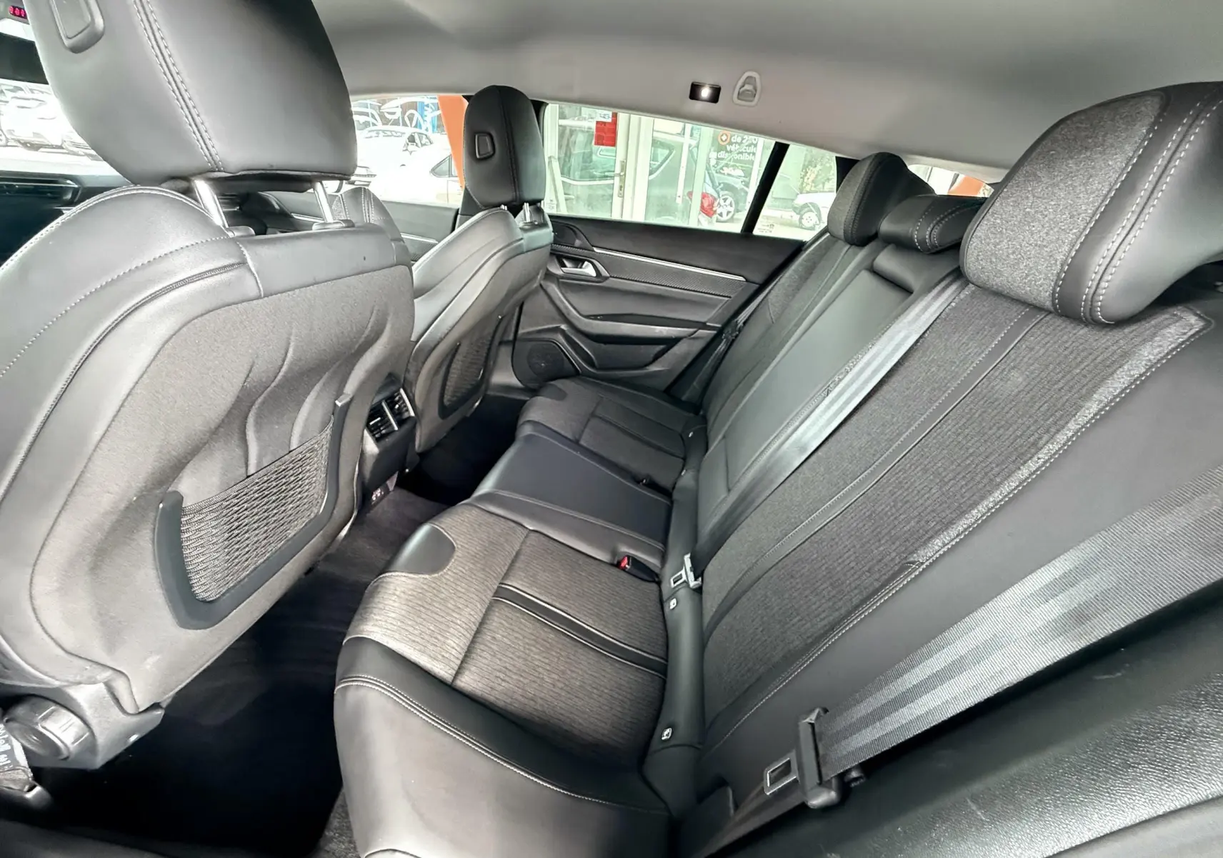 Vue latérale intérieure des sièges arrière noirs en tissu et cuir de la Peugeot 308 SW 2018.