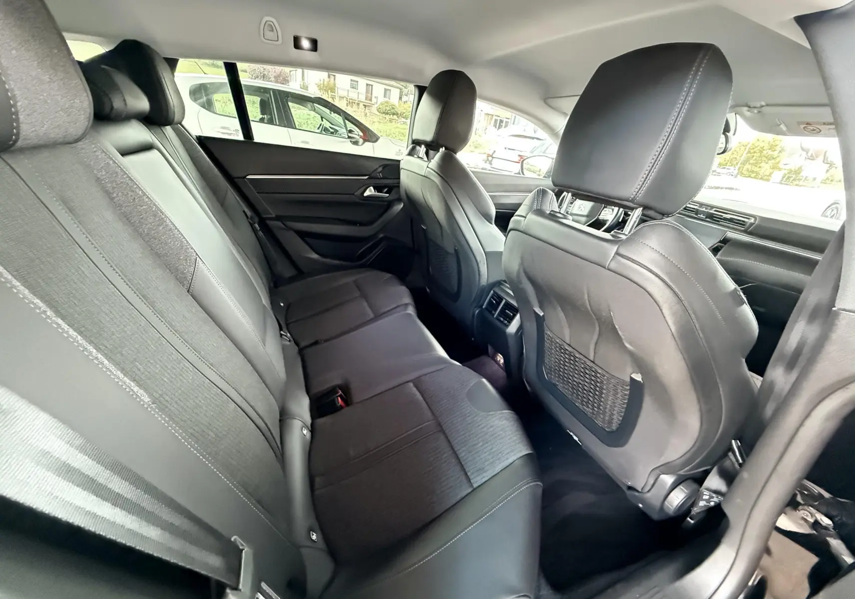 Intérieur arrière de la Peugeot 308 SW noir, vue côté droit montrant les sièges en tissu et cuir avec appuie-têtes.