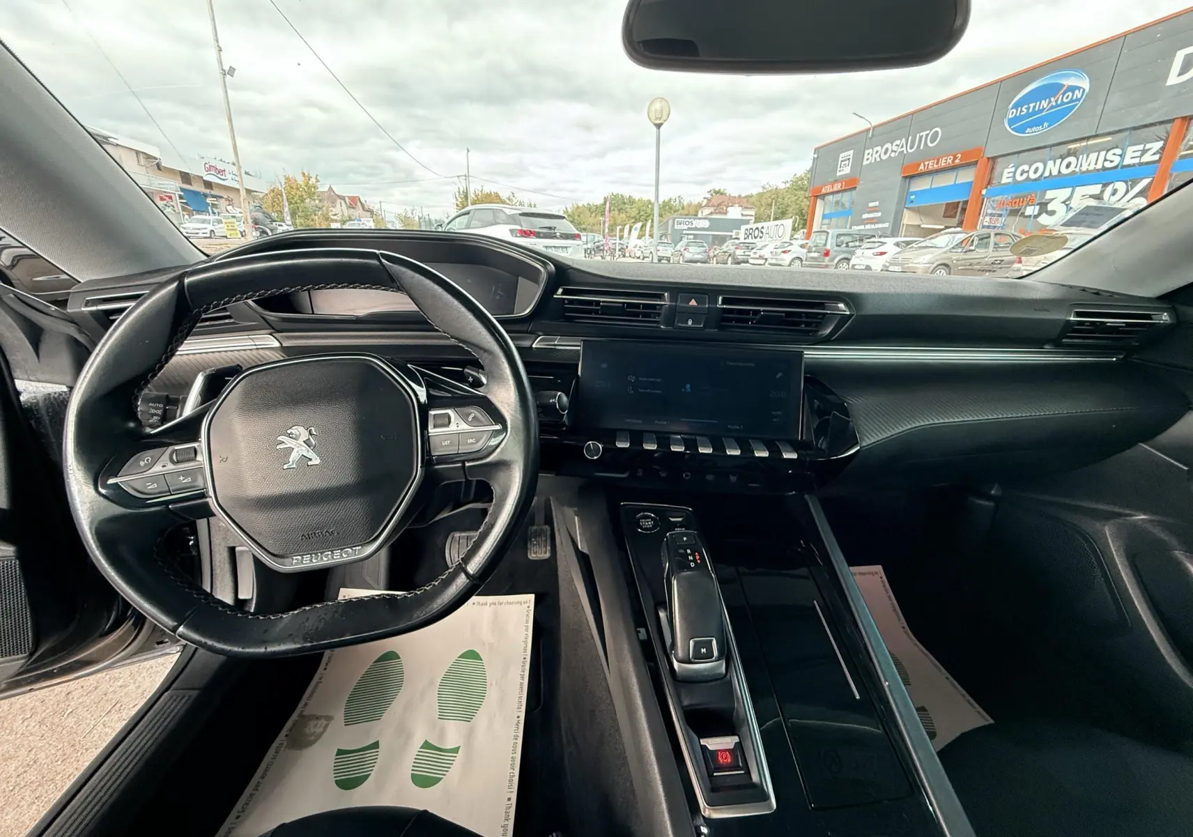 Vue intérieure du poste de conduite noir d'une Peugeot 308 SW 2018, avec volant compact et écran tactile central.