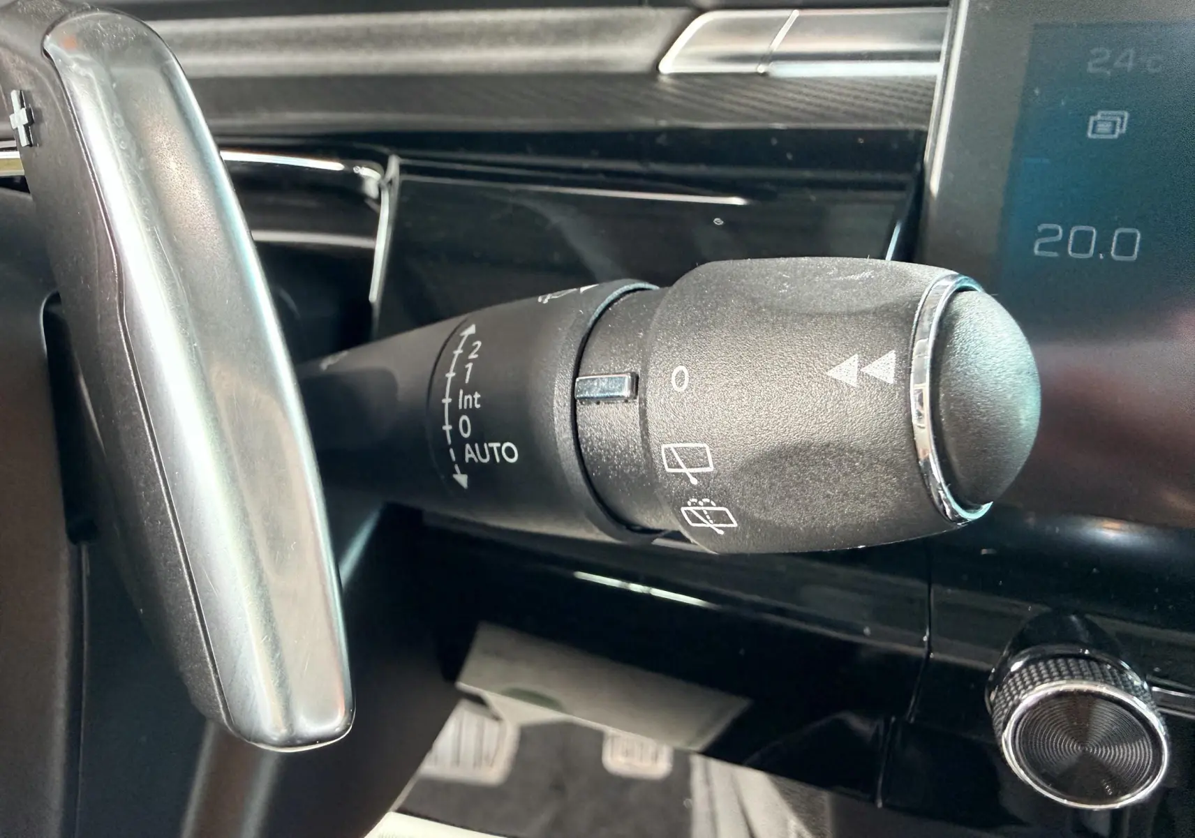 Gros plan sur la commande d'essuie-glace à gauche du volant dans l'habitacle noir d'une Peugeot 308 SW 2018.