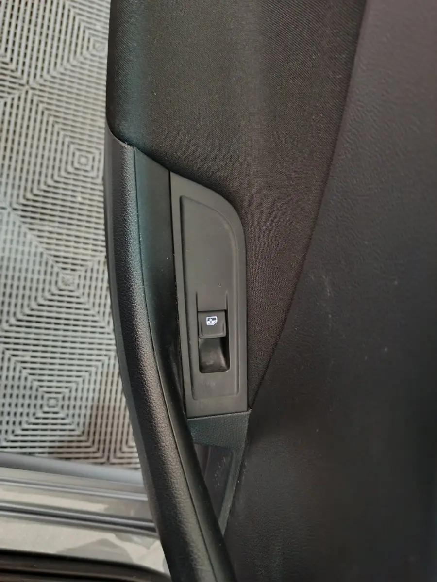 Gros plan sur le bouton de verrouillage des portes côté intérieur d'une Skoda Kamiq gris clair 2024.