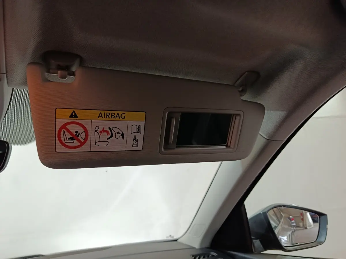 Vue intérieure du pare-soleil côté conducteur avec miroir et avertissement airbag dans un Skoda Kamiq gris clair 2024.