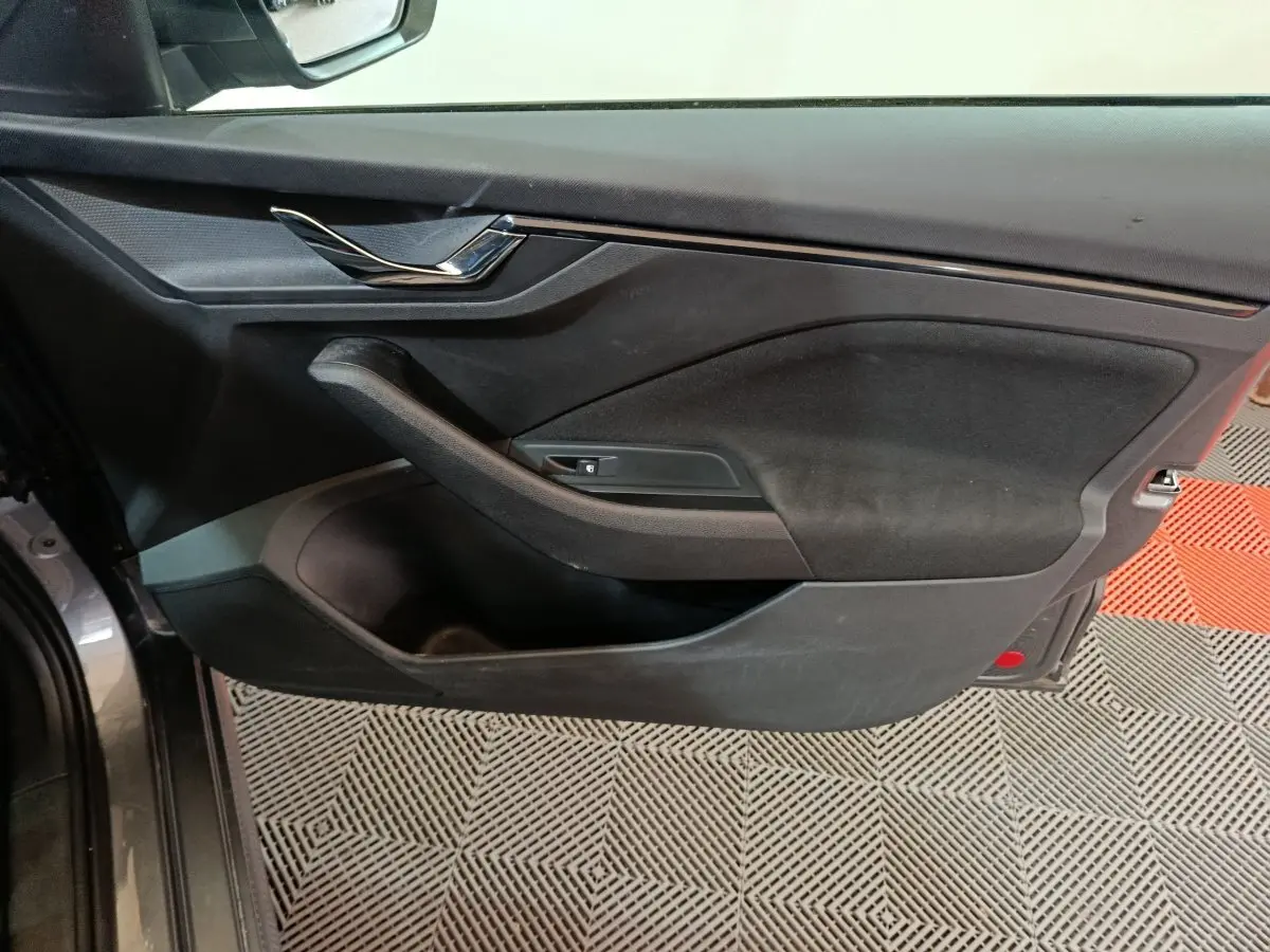 Vue côté gauche de la porte avant gris clair d’un Skoda Kamiq 2024 avec poignée chromée et rangement intégré.