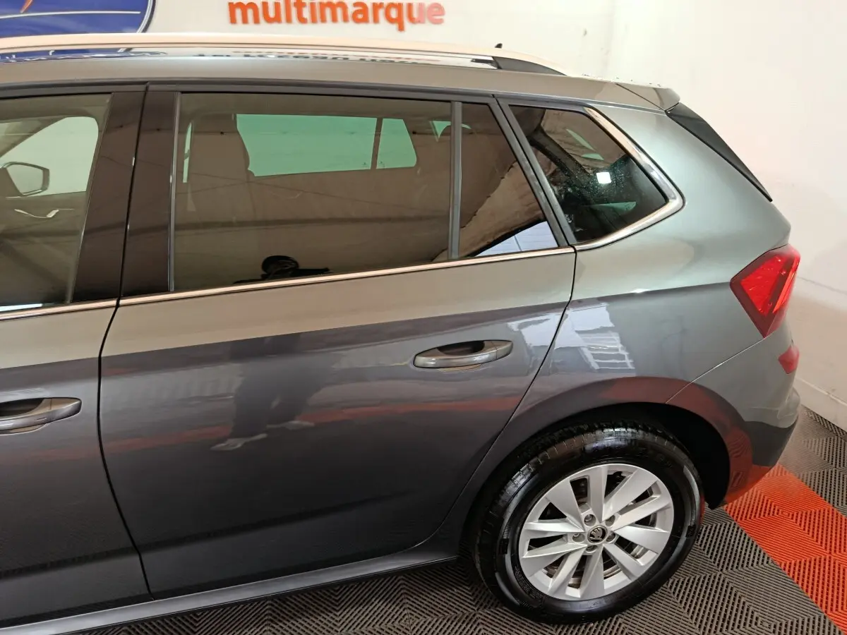 Vue côté droit arrière d'un Skoda Kamiq gris clair avec jante alliage et vitres teintées.