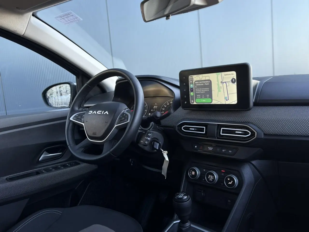Vue intérieure côté conducteur du tableau de bord du Dacia Jogger gris avec écran tactile GPS et volant multifonction.