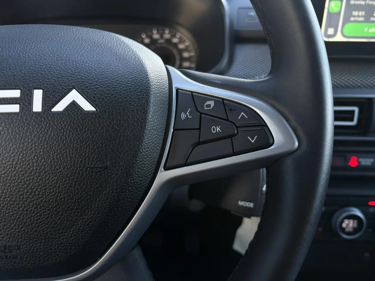 Gros plan sur le volant noir de la Dacia Jogger 2025 avec commandes multifonctions et partie centrale texturée.
