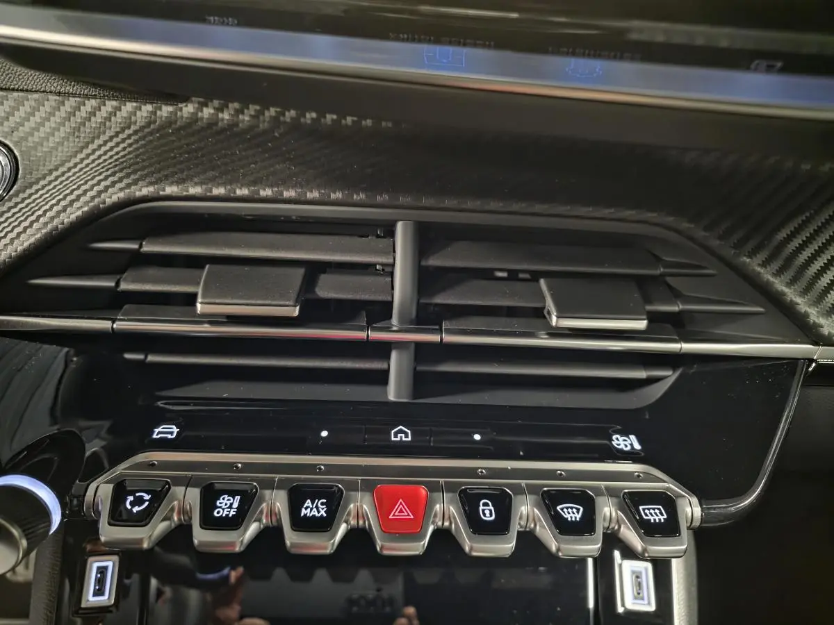 Détail de la console centrale du Peugeot 2008 gris 2025, avec aérateurs et rangée de boutons fonctionnels éclairés.