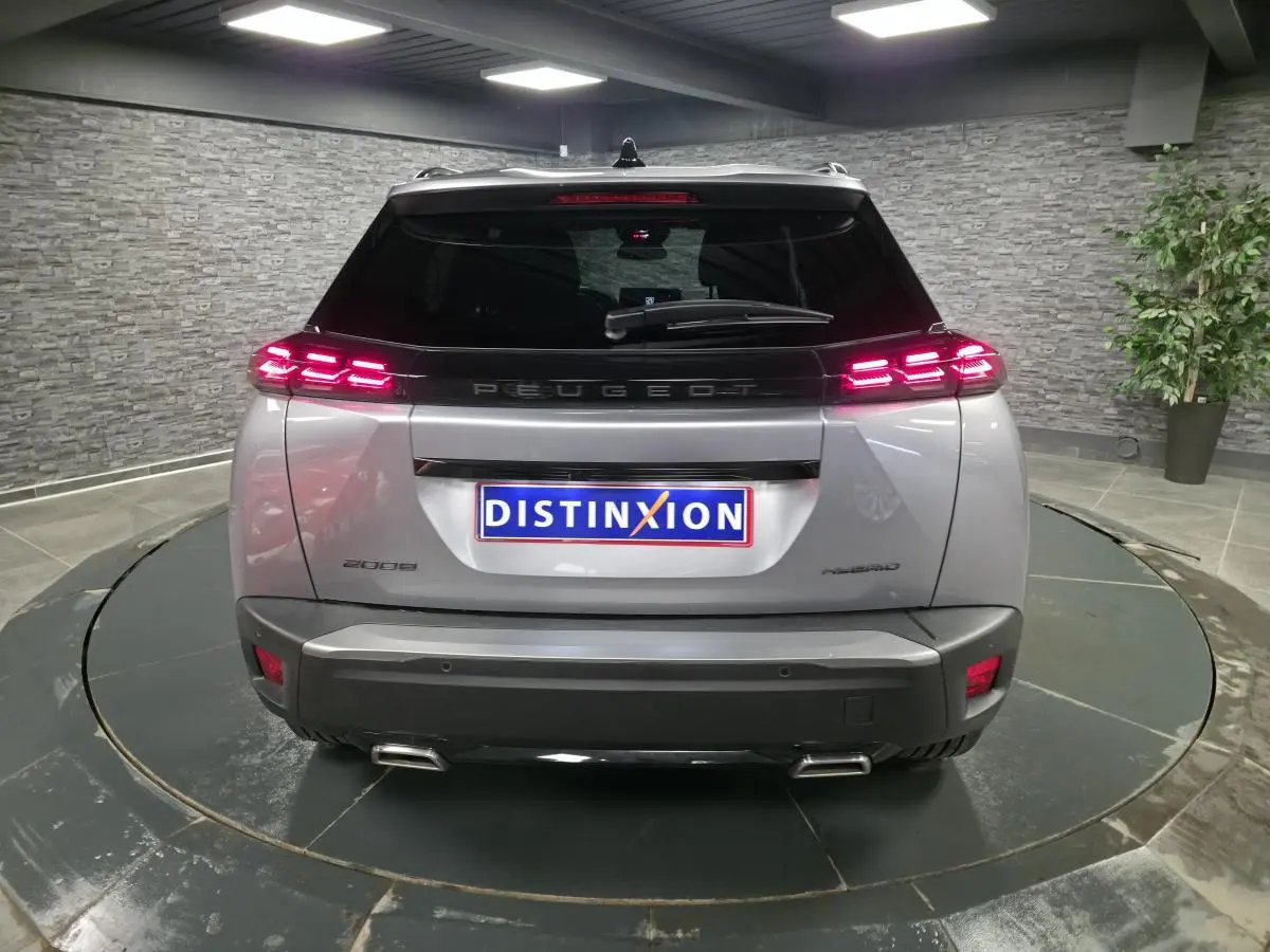 Vue arrière d'un Peugeot 2008 gris avec feux LED allumés et double canule d'échappement chromée dans un showroom.