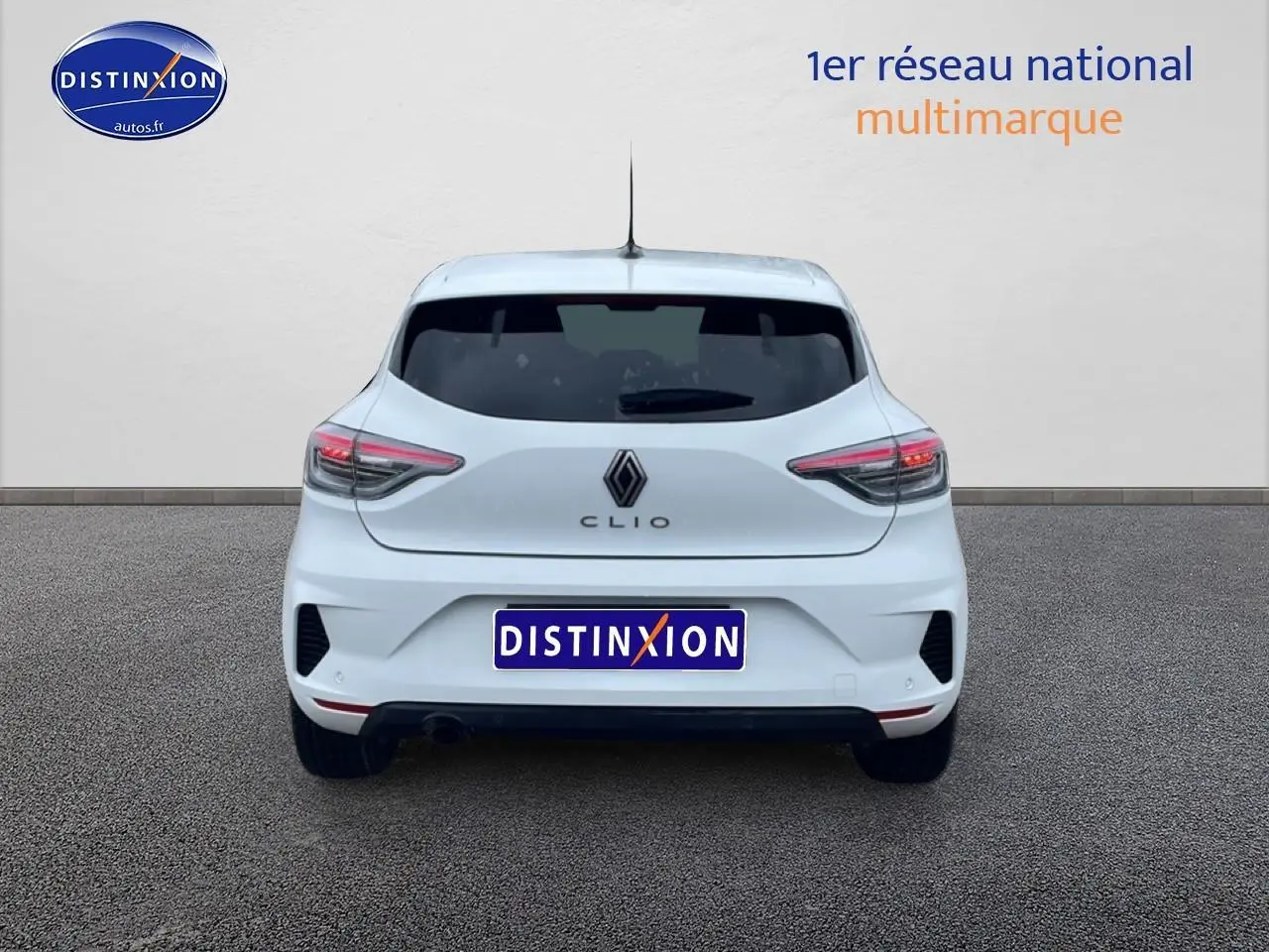 Vue arrière d'une Renault Clio V blanche avec feux LED et logo Renault visible sur un sol gris.