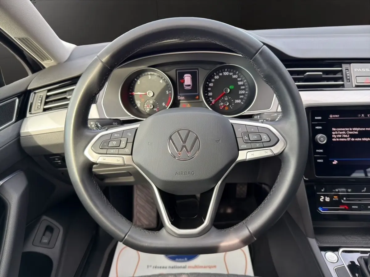 Vue intérieure centrée sur le volant cuir noir et le tableau de bord numérique de la Volkswagen Passat 2.0 TDI 2022.