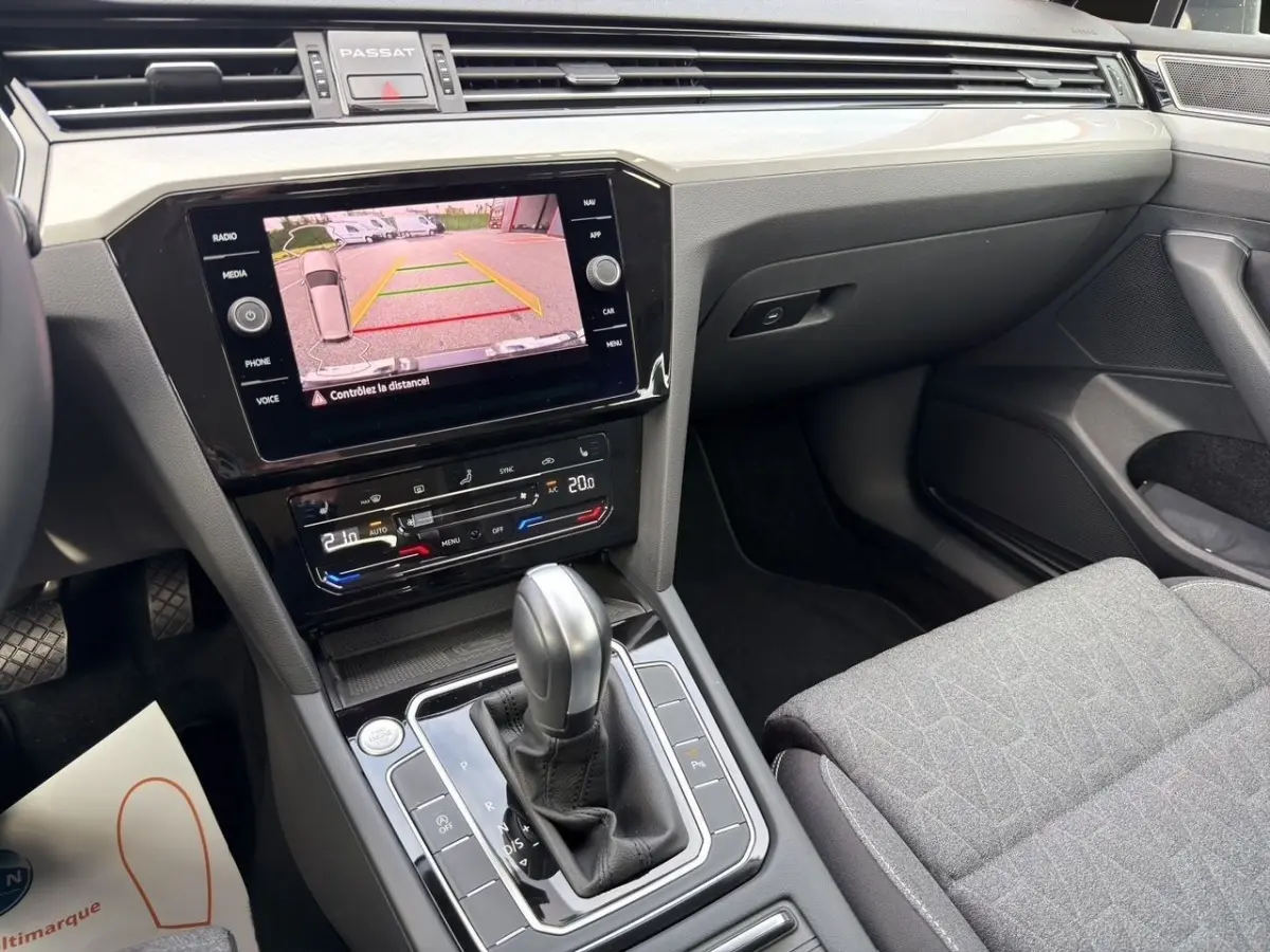 Vue intérieure côté passager de la Volkswagen Passat gris foncé, avec écran tactile affichant la caméra de recul.