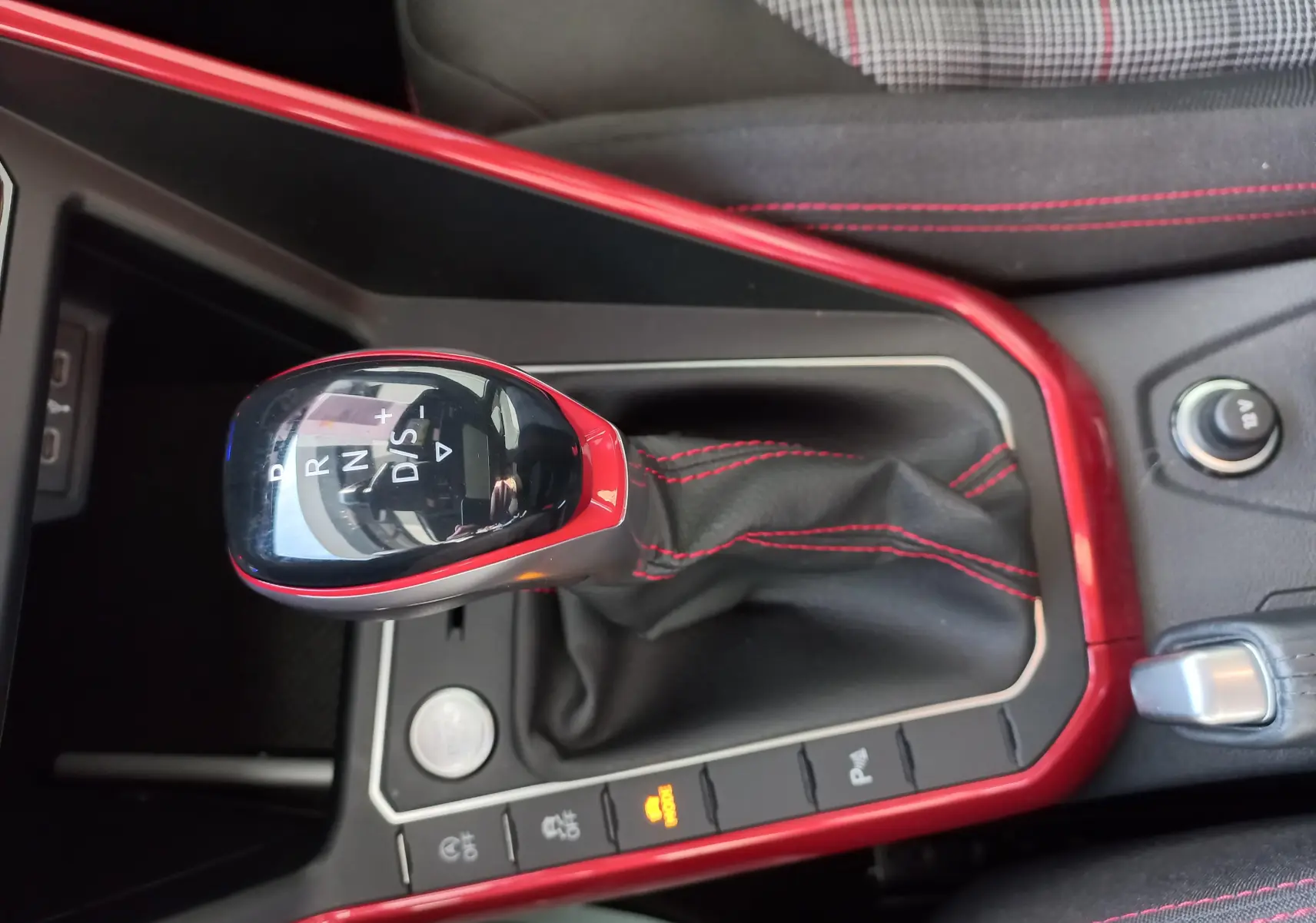 Gros plan sur la commande de boîte automatique DSG7 avec contour rouge et surpiqûres rouges dans l'habitacle d'une Volkswagen Polo GTI.