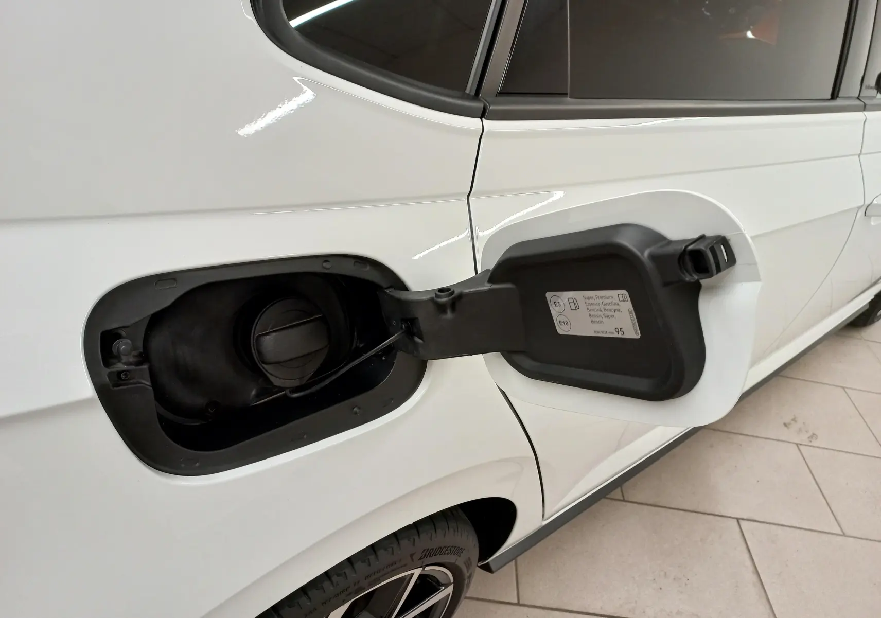 Vue latérale droite rapprochée d’une Volkswagen Polo blanche avec trappe à carburant ouverte sur fond intérieur.