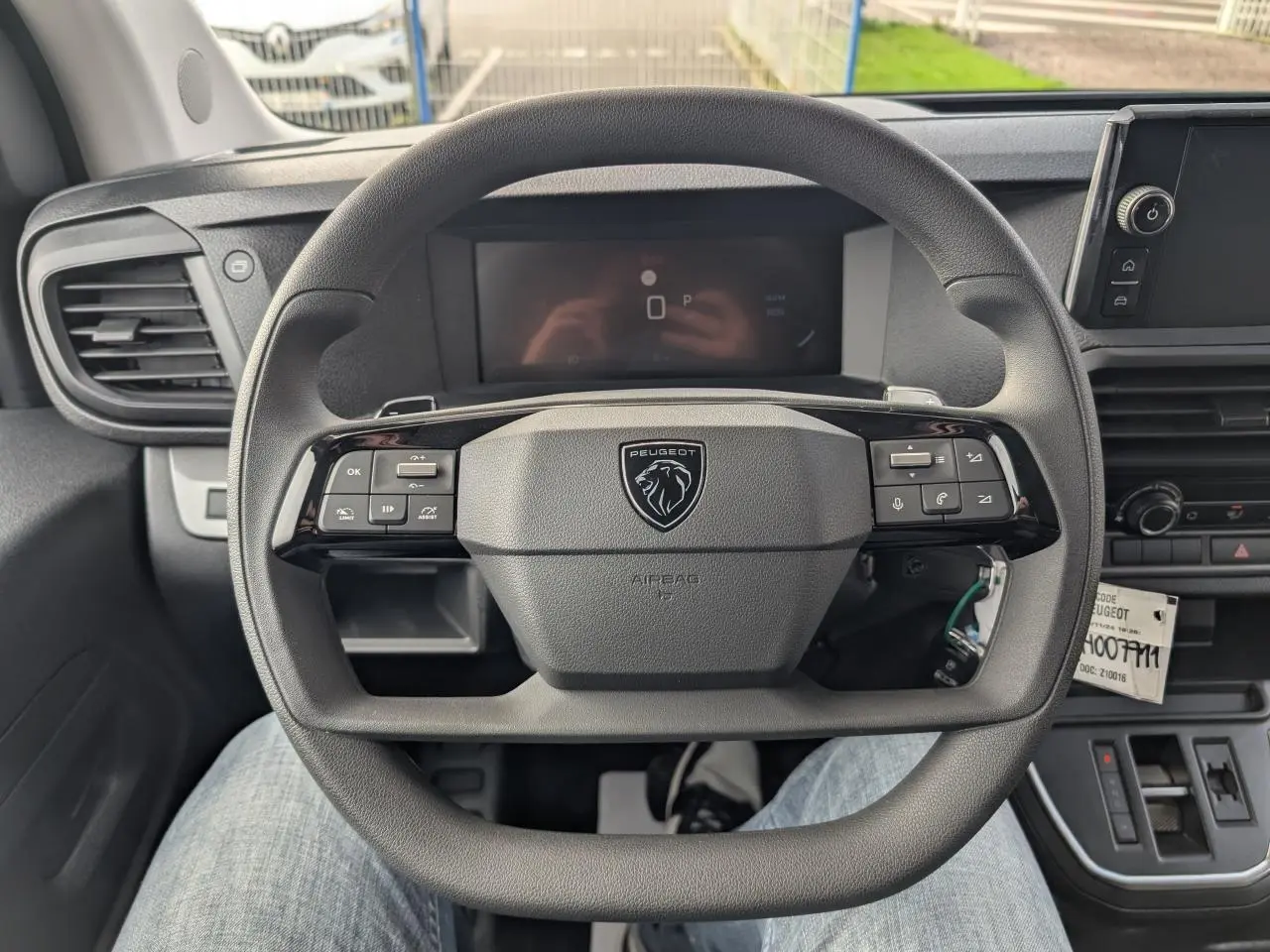 Vue rapprochée du volant noir du Peugeot Expert Fourgon 2025 avec commandes intégrées et combiné numérique en arrière-plan.