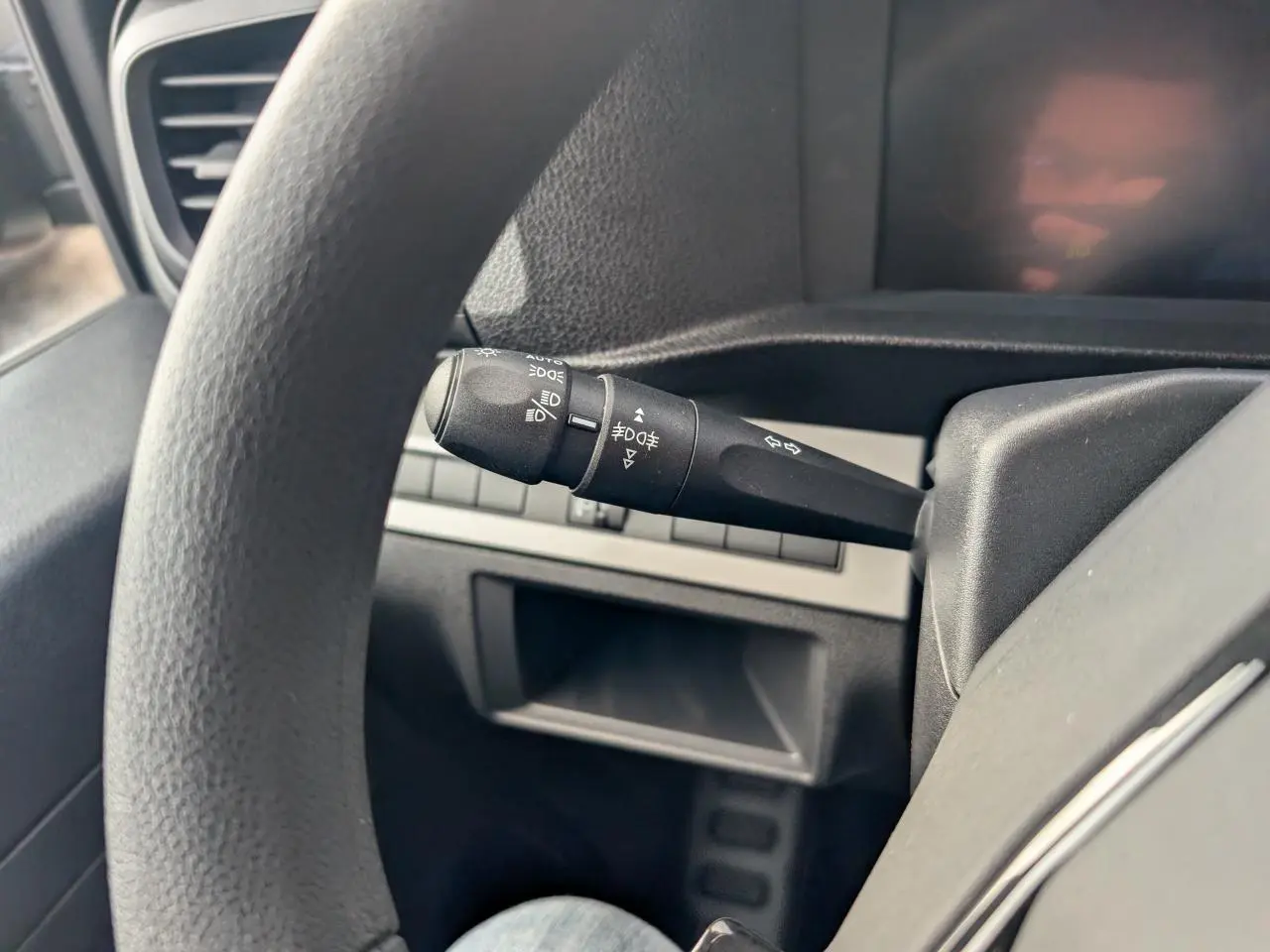Détail de la commande de phares et clignotants côté gauche du volant dans l'habitacle noir du Peugeot Expert Fourgon 2025.