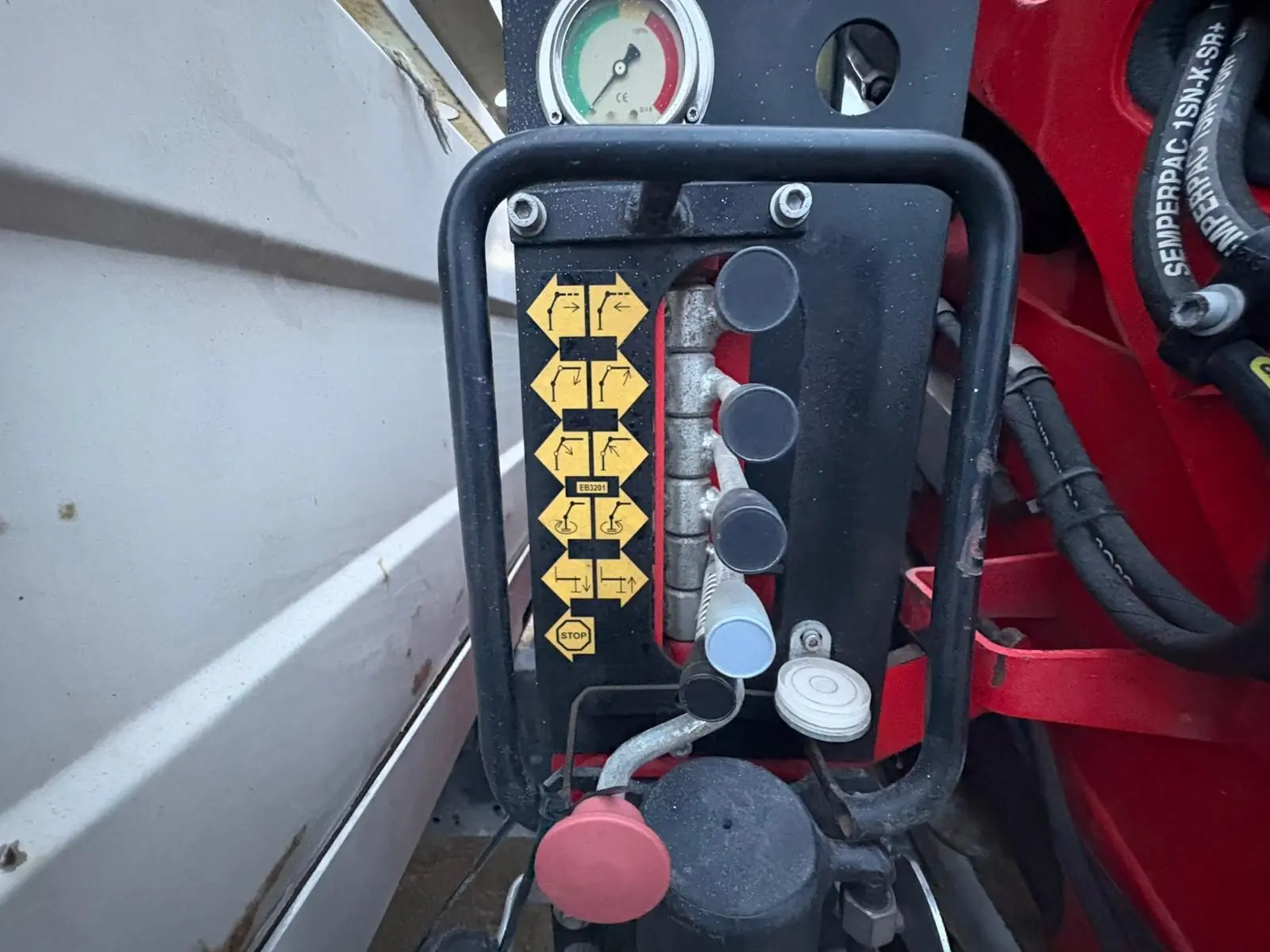 Gros plan sur les commandes de la grue rouge Palfinger du côté gauche de la benne blanche du camion Iveco Daily Chassis Cabine.