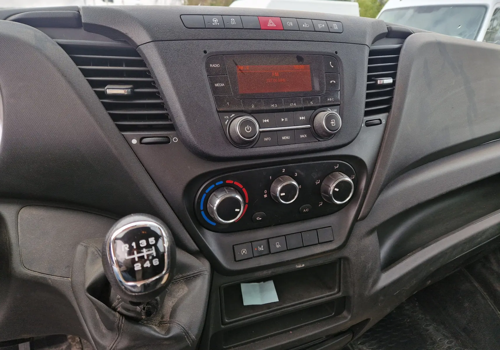 Vue intérieure du tableau de bord Iveco Daily 35C14 avec boîte manuelle, commandes climatisation et radio intégrées.