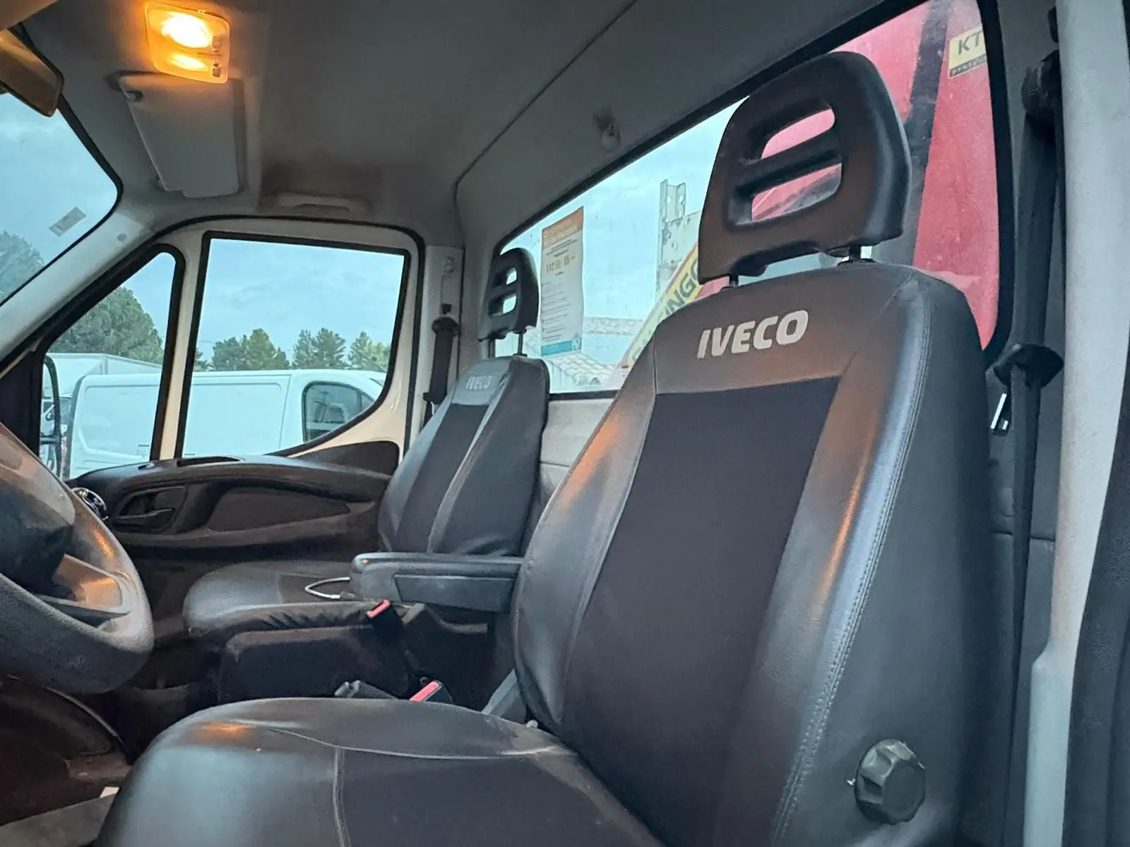 Vue intérieure côté conducteur de l’Iveco Daily 35C14 2021, sièges noirs avec logo Iveco visibles.