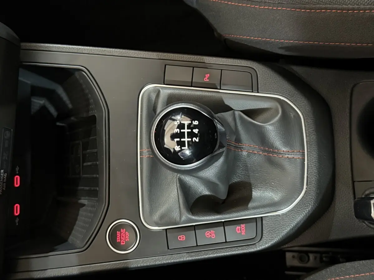 Vue rapprochée du levier de vitesses manuel noir avec coutures rouges dans une SEAT Ibiza blanche 2024.